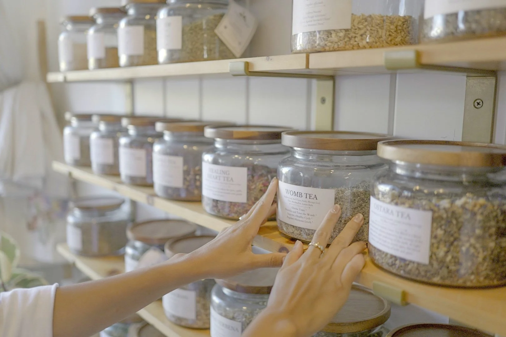 Hand selecting from jars of herbal remedies