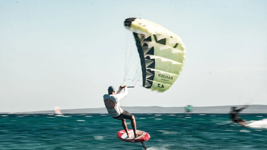 A person is Parawing Downwinding at La Ventana bay on the ocean with a yellow and black Parawing.