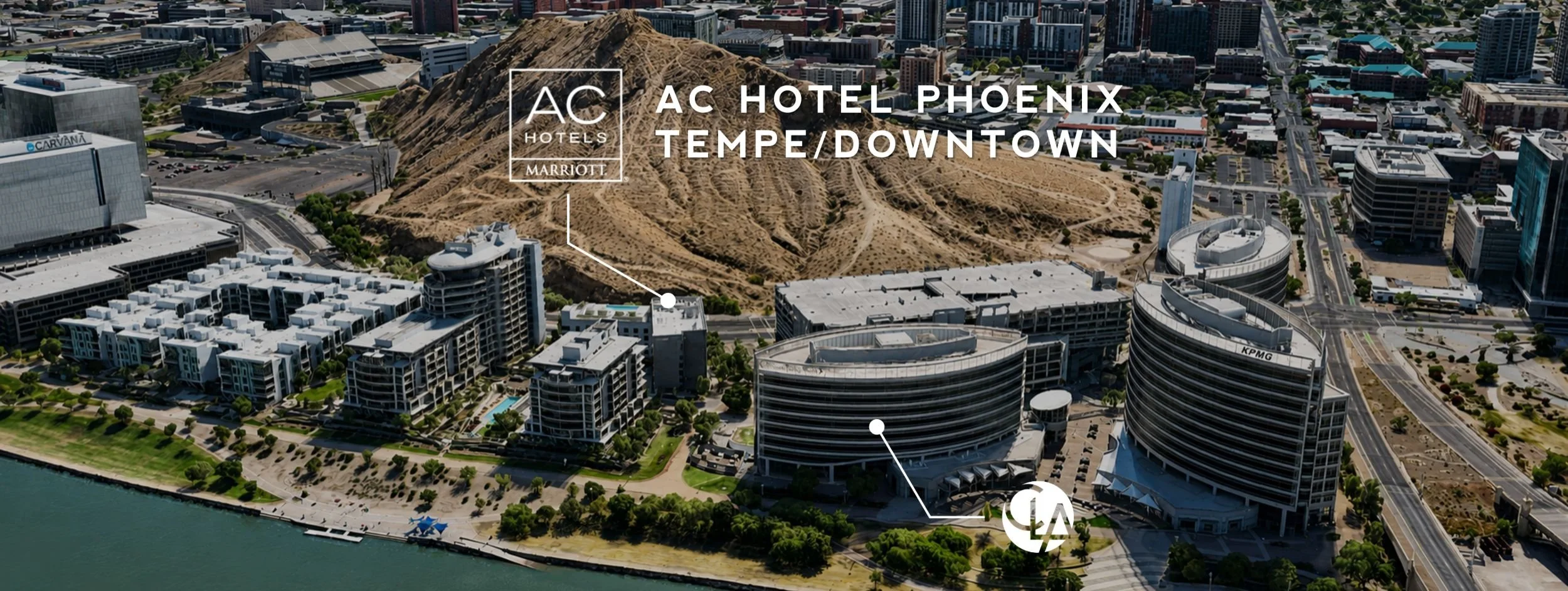 Aerial view of downtown Phoenix, Arizona, featuring mountains, modern buildings, and the waterfront with a pool and green park area.