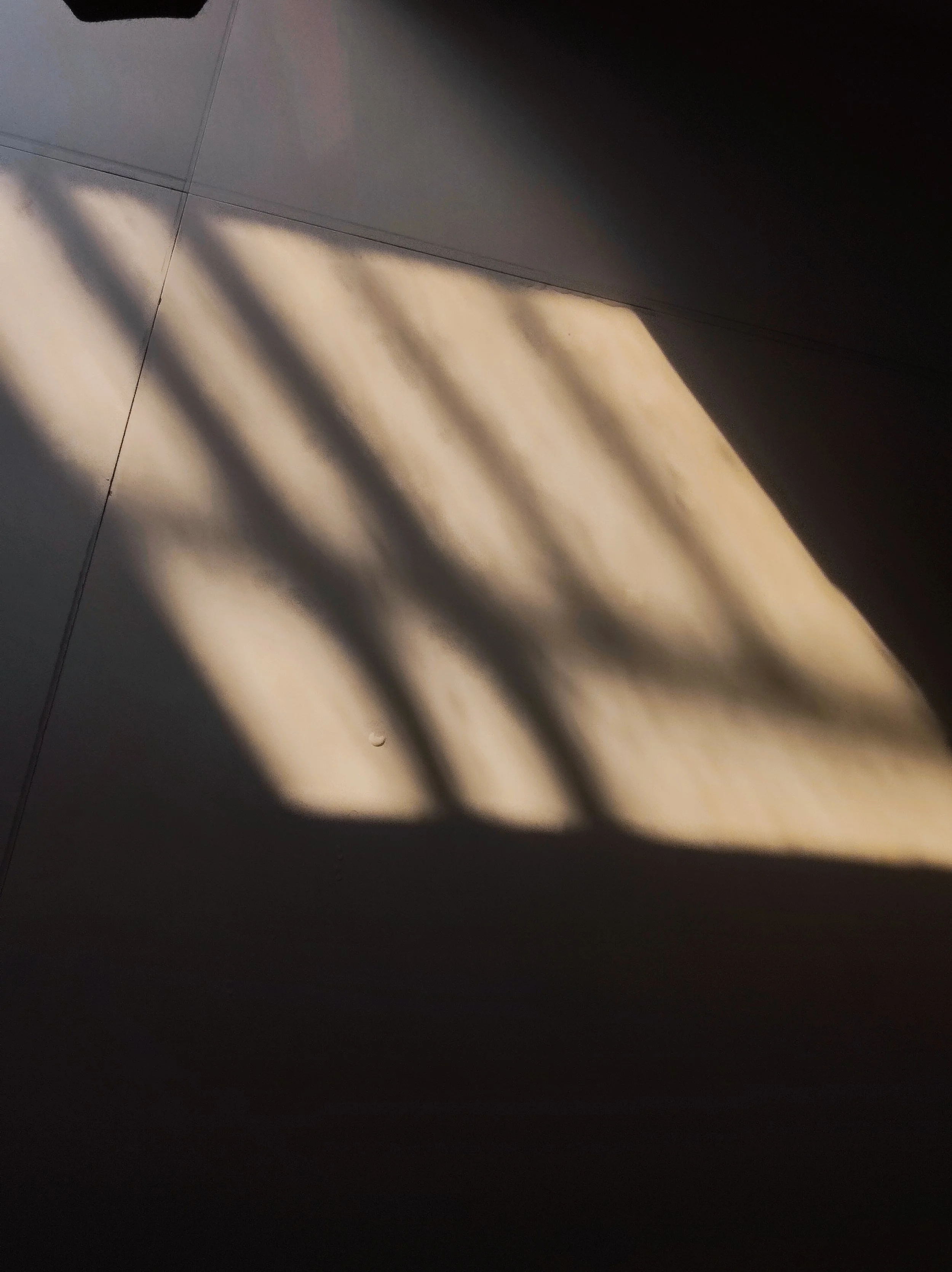 Natural light casting geometric shadows across a tiled floor, illustrating the role of light in shaping atmosphere.