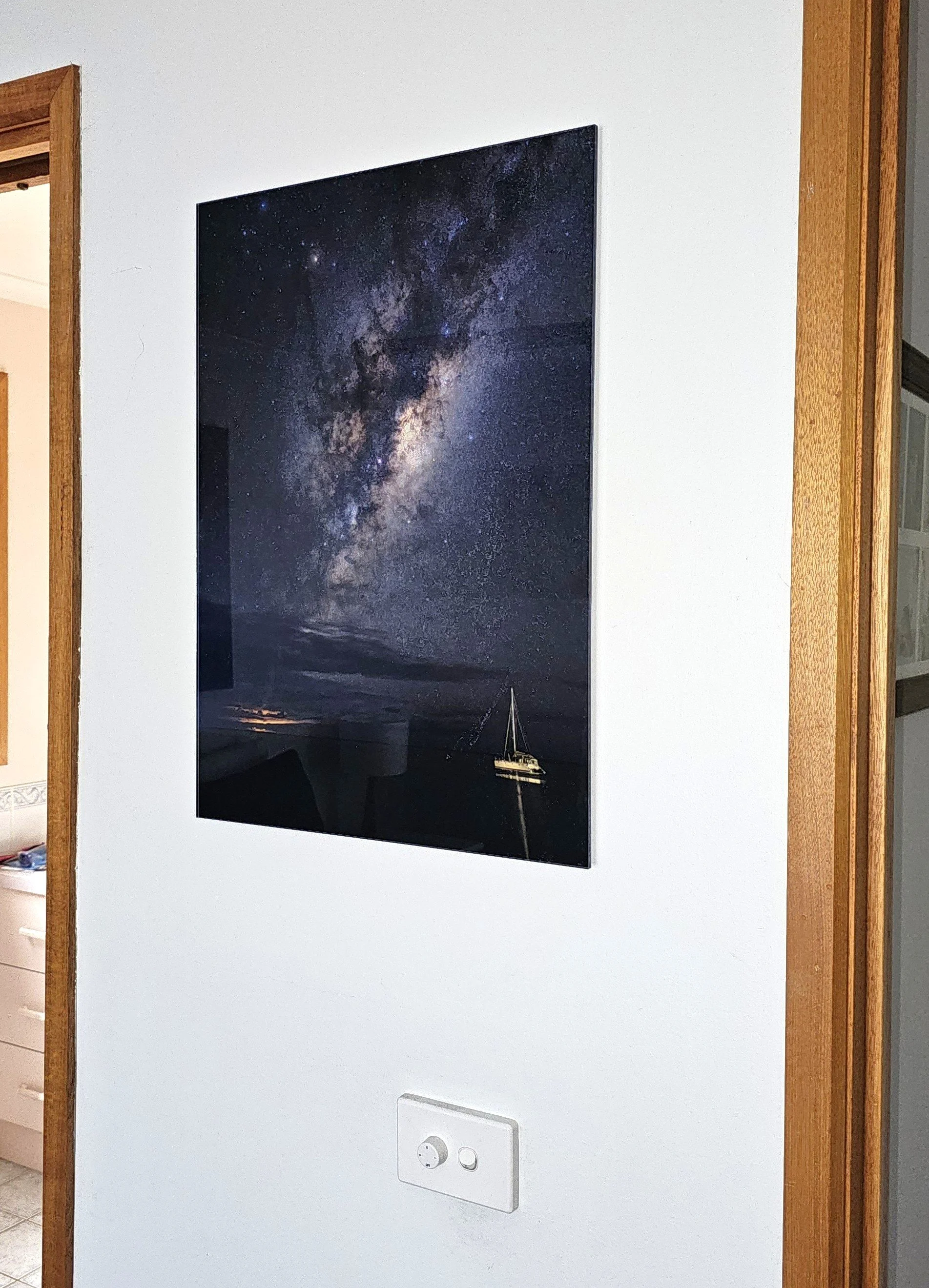 Wall-mounted flat-screen TV displaying a galaxy scene, with a sailboat visible at the bottom.