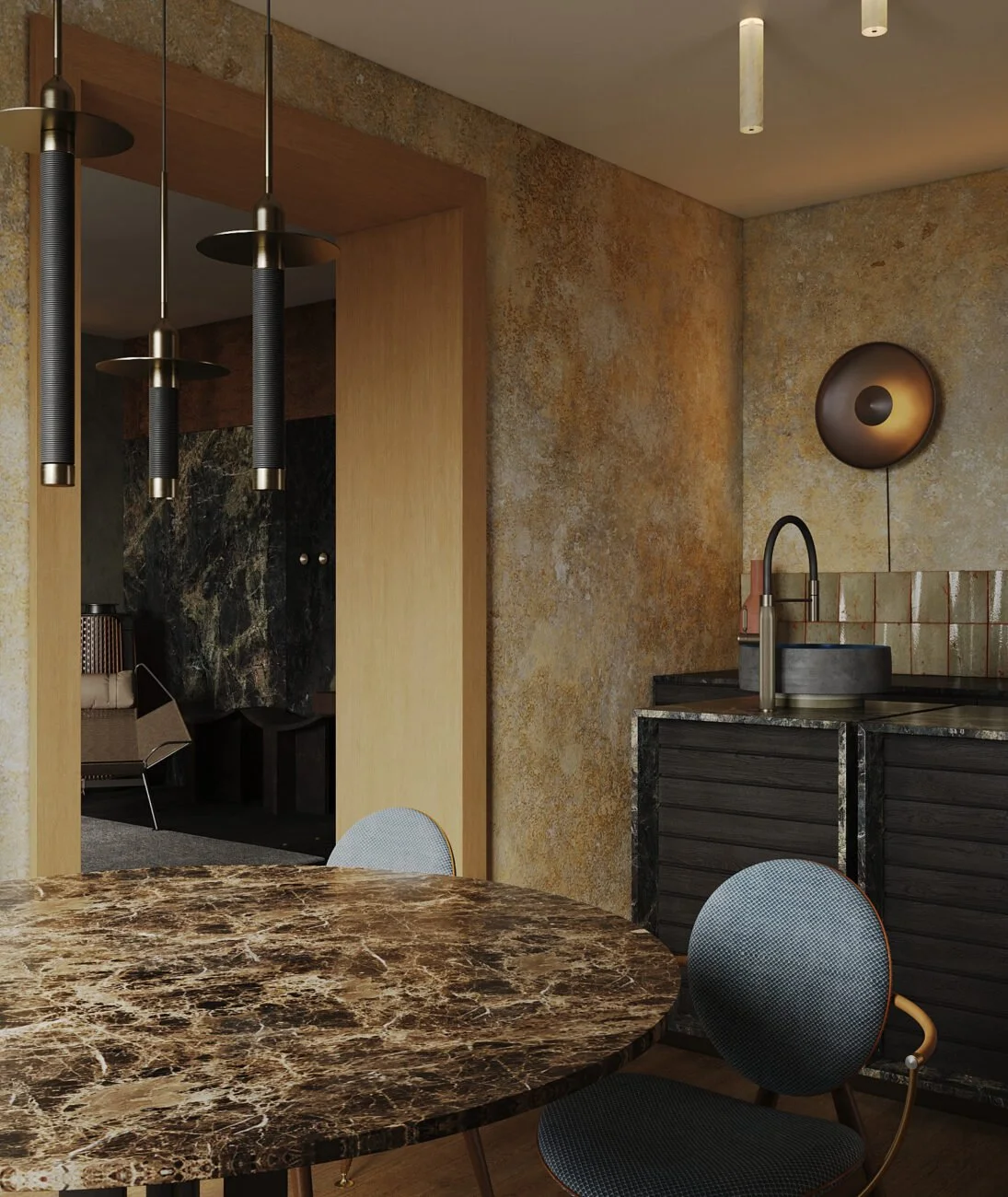 Innenaufnahme einer modernen Küche mit dunklem Marmor-Esstisch, schwarzen Unterschränken, Wandlampen, und einem schwarzen Wasserhahn vor einem goldbraunen Wand. Im Hintergrund ein Raum mit Sitzmöbeln und dunkel geboastem Marmor.