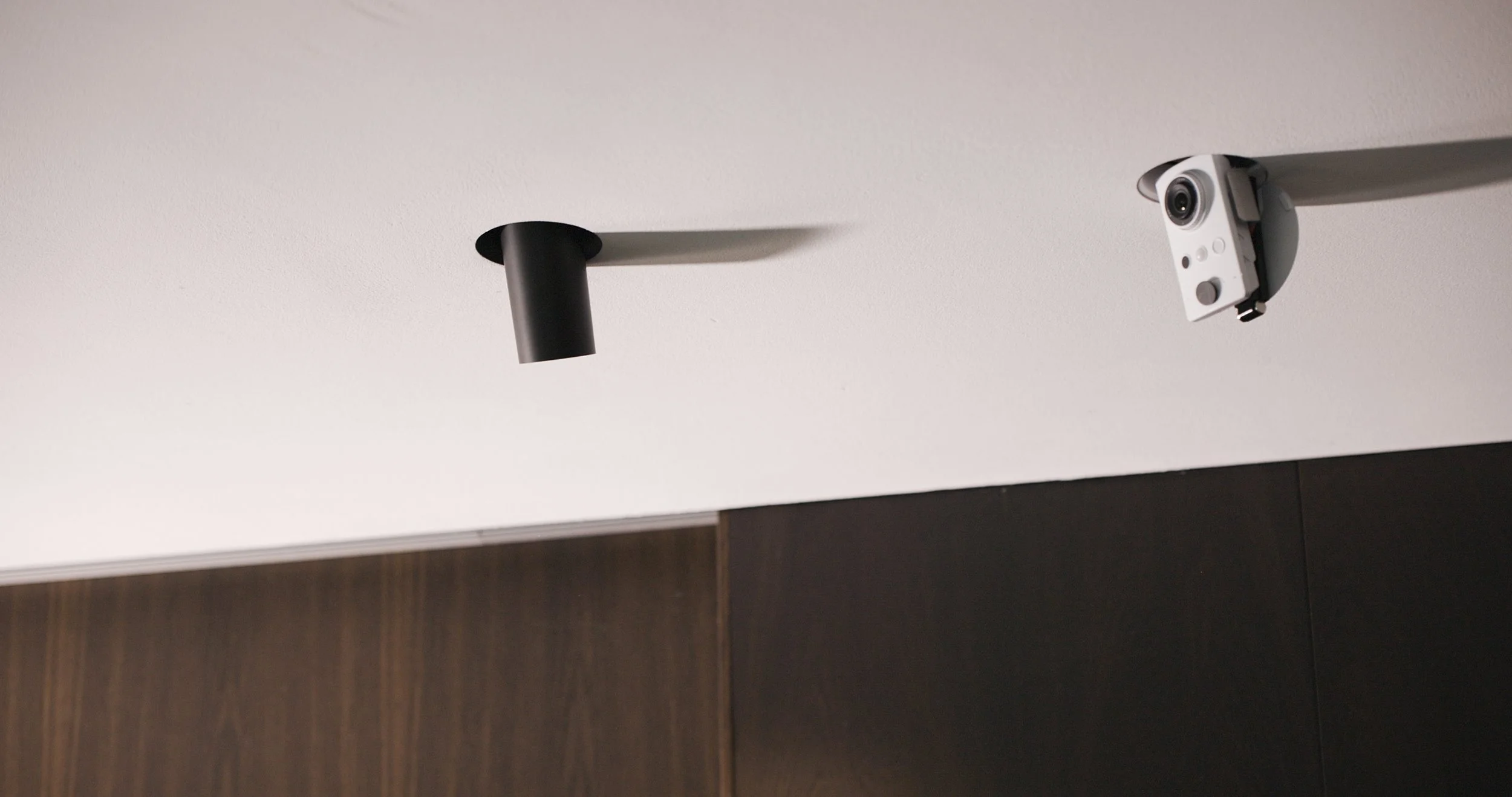 Decke mit einer schwarzen Deckenleuchte und einer Wand mit dunklem Holzvertäfelung, eine Sicherheitskamera