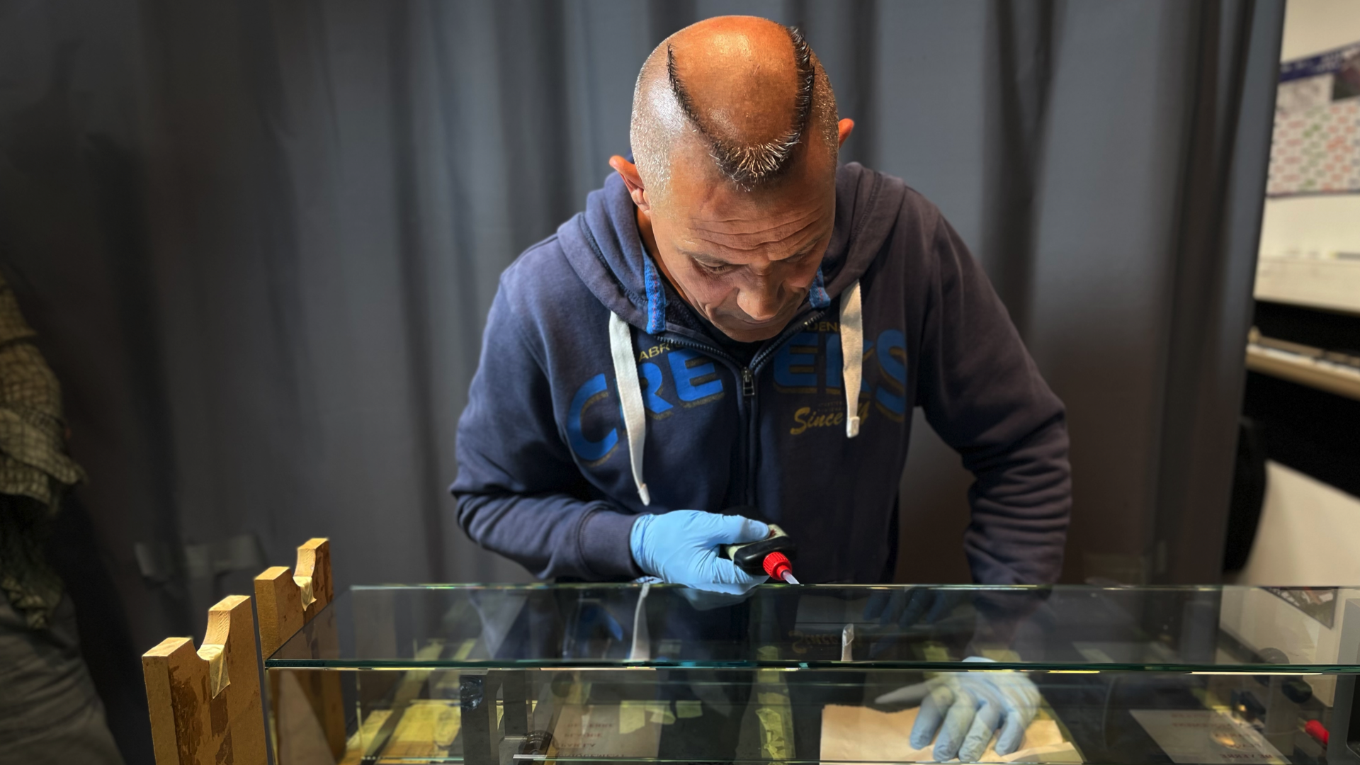 Ein Waterfall Audio Mitarbeiter trägt blaue Handschuhe und verwendet eine Pipette, um Flüssigkeit auf eine optische Platte oder Glasplatte zu übertragen. Ein Waterfall Audio Lautsprecher entsteht.