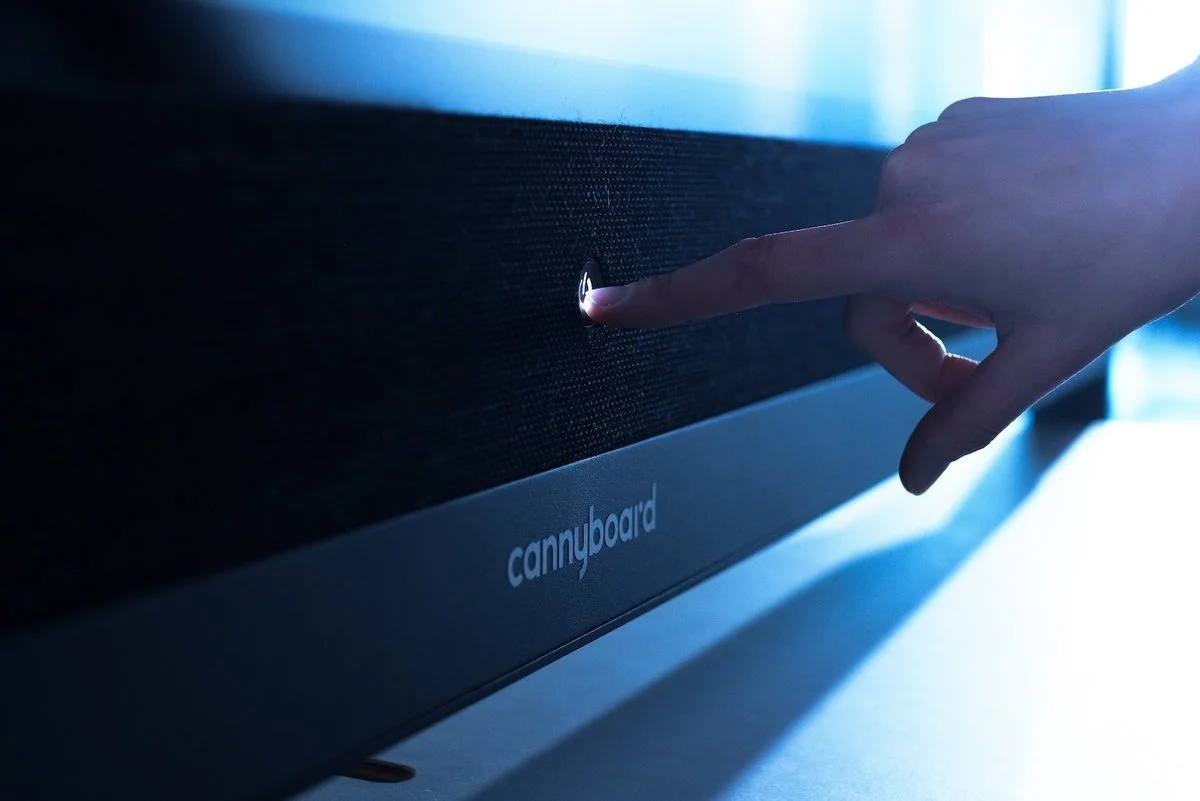 Nahaufnahme eines Fingers, der auf einen Knopf an einem modernen elektronischen Gerät drückt, das mit der Marke 'cannyboard' gekennzeichnet ist.