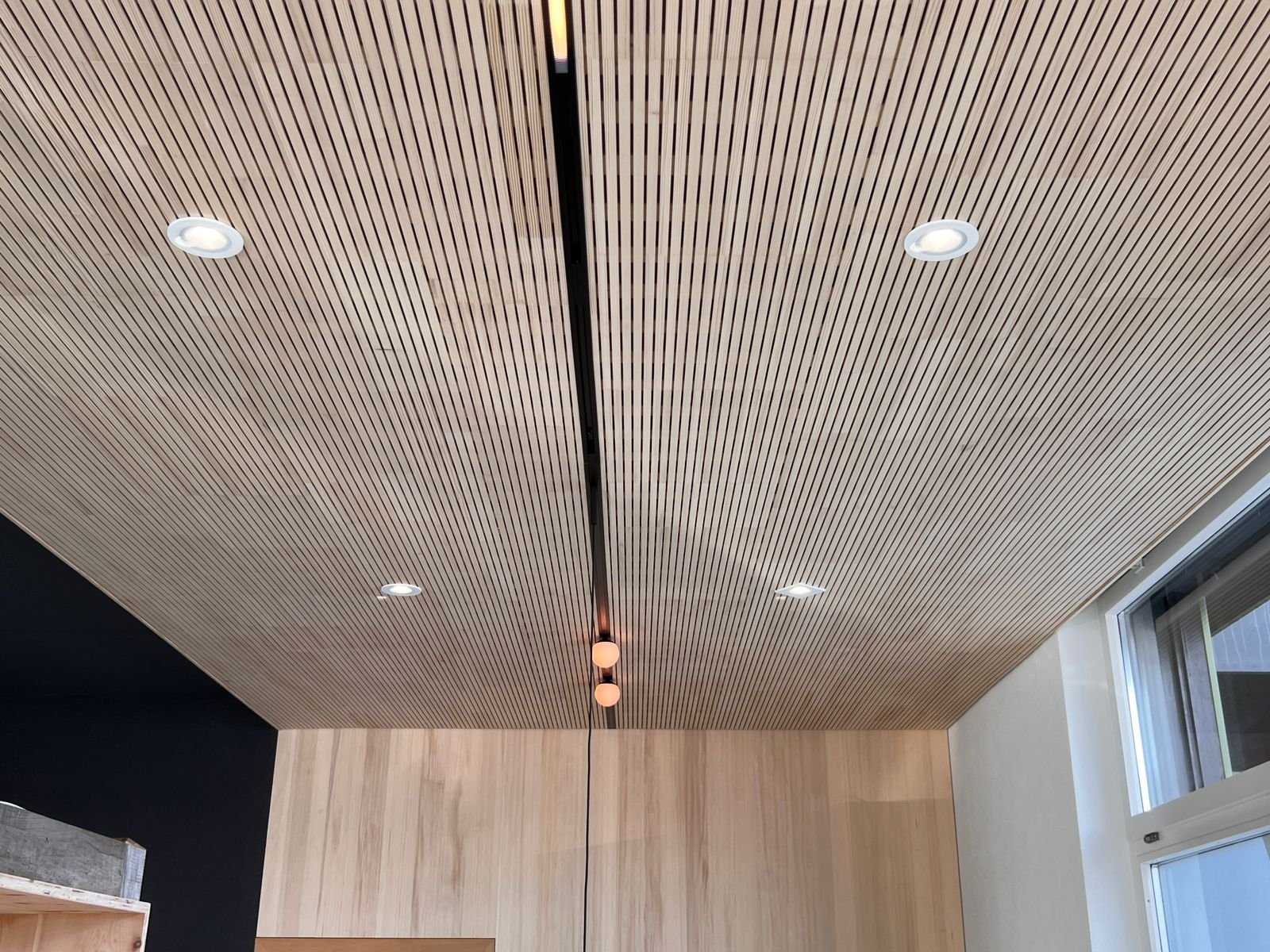 Moderne Holztapeten an der Decke mit integrierter Beleuchtung in einem Raum.