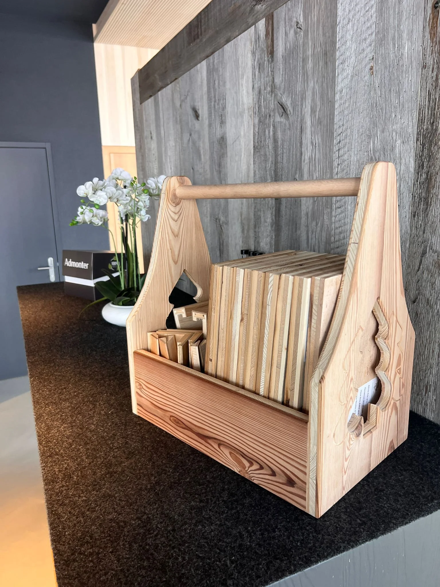 Ein Holzkasten auf einer dunklen Arbeitsplatte mit Pappe und Blumen