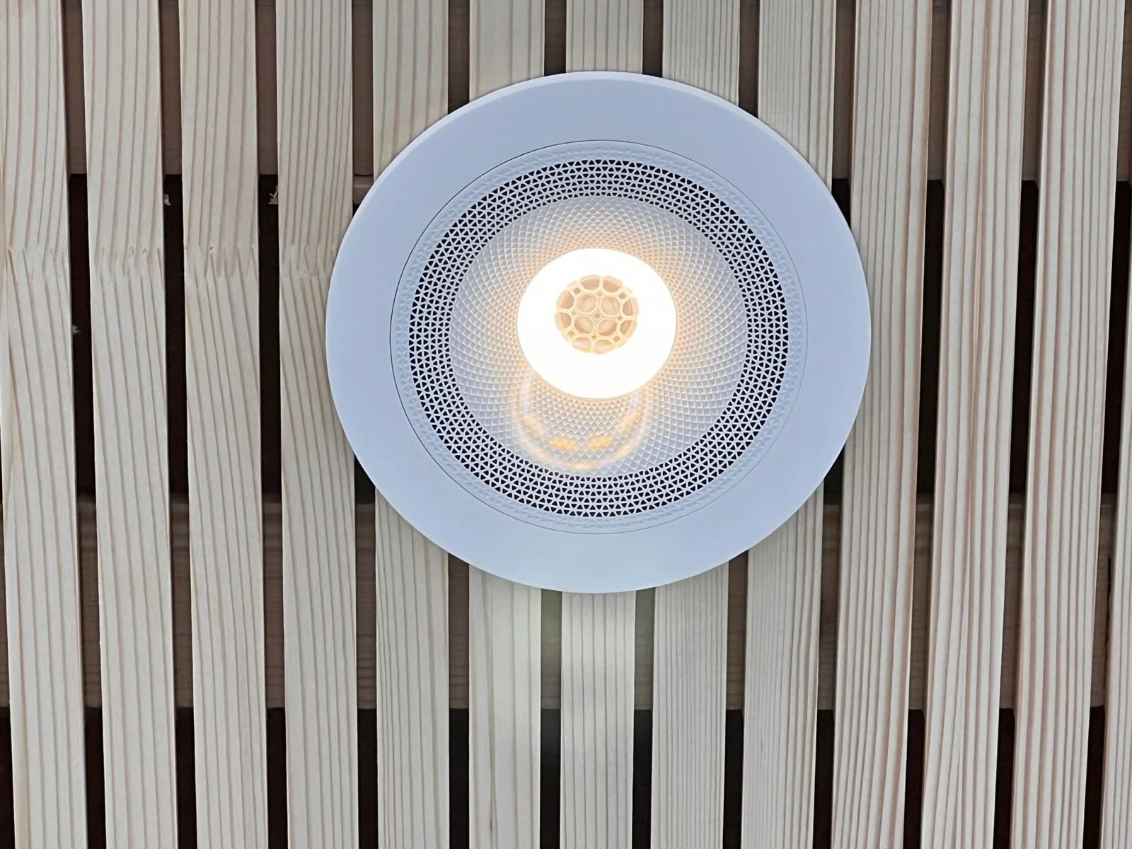 Deckenleuchte an einer Holzdecke, moderne runde Beleuchtung mit Diffusor und Muster