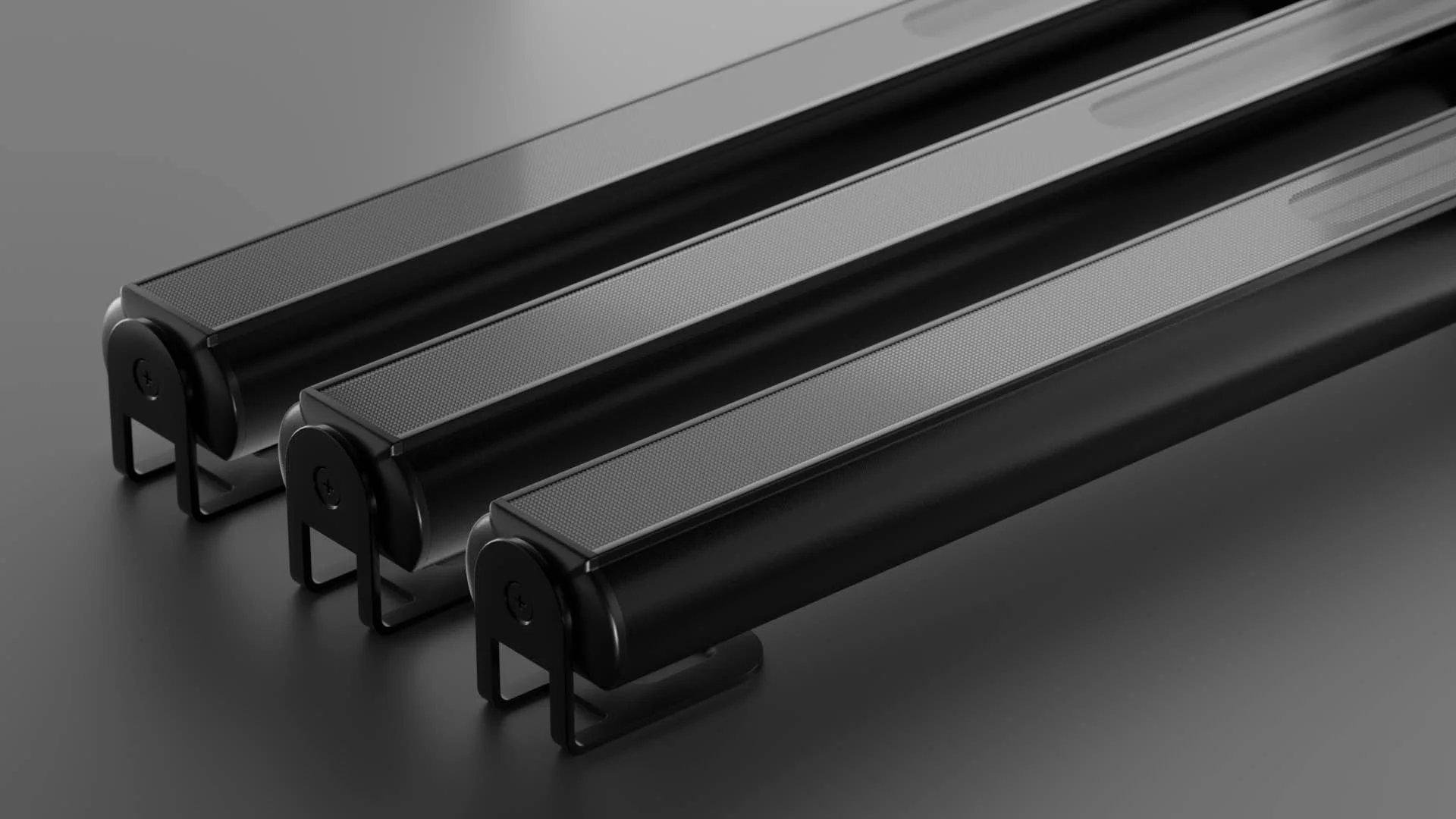 Drei schwarze LED-Scheinwerfer mit Metallgehäuse und Standfüßen, auf einer dunklen Oberfläche platziert.