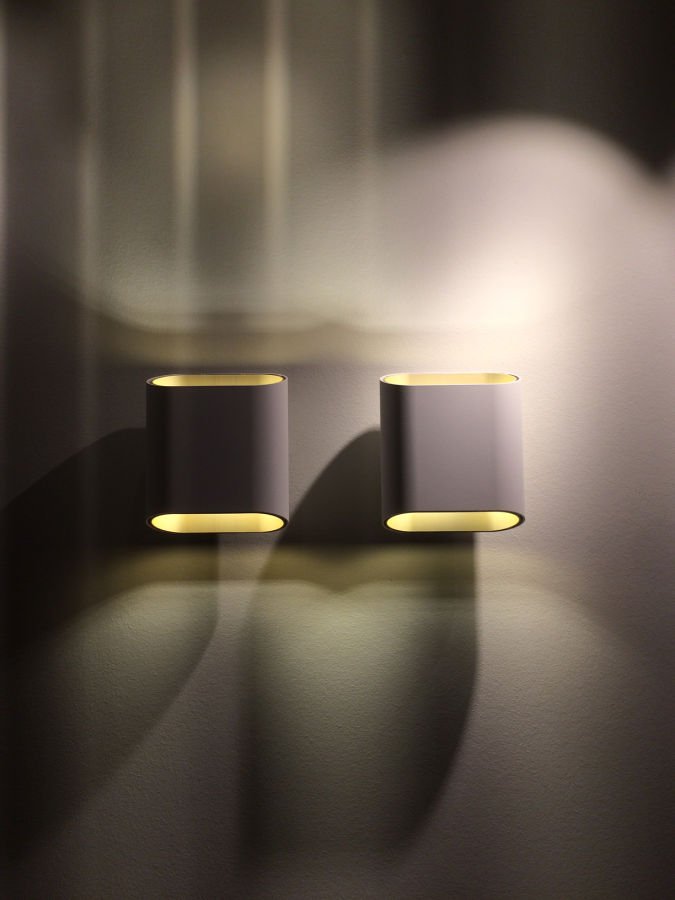 Zwei kleine, runde Lampen auf einer dunklen Oberfläche, die warme, indirekte Beleuchtung erzeugen.