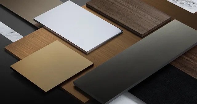 Verschiedene Holz- und Materialproben, darunter weiße, braune, goldene, schwarze und gemusterte Oberflächen, auf einem Tisch ausgelegt.