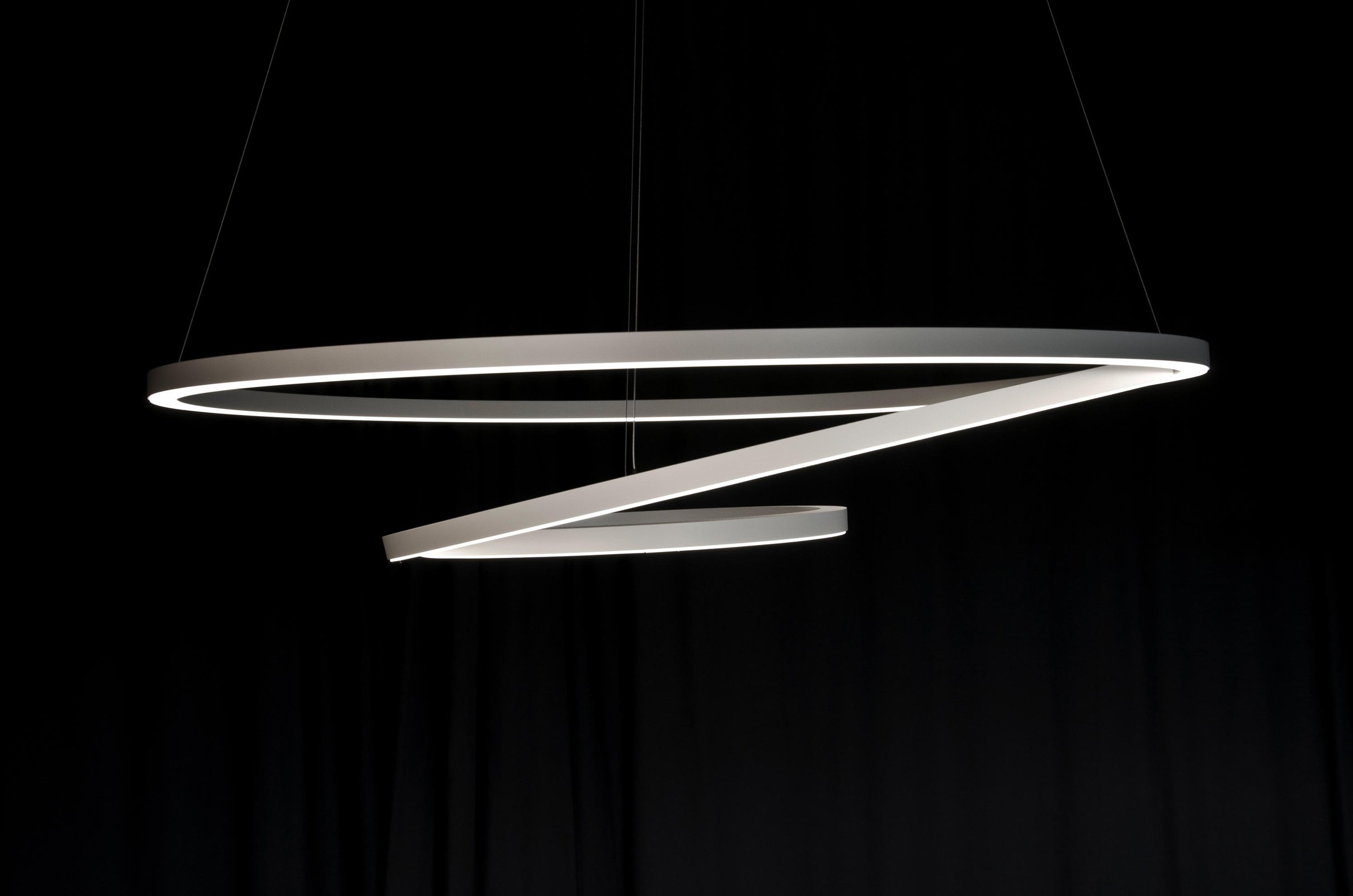 Moderne, spiralförmige LED-Deckenleuchte vor schwarzem Hintergrund.