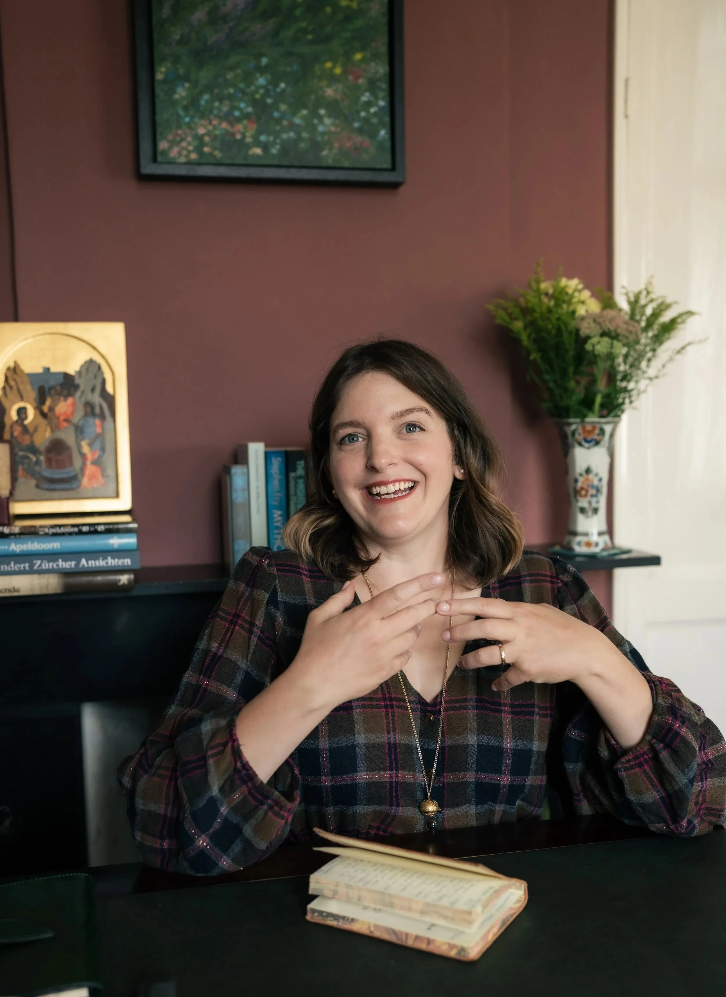 Nora Keller sitting at her desk in her library, gesticulating as she talks.