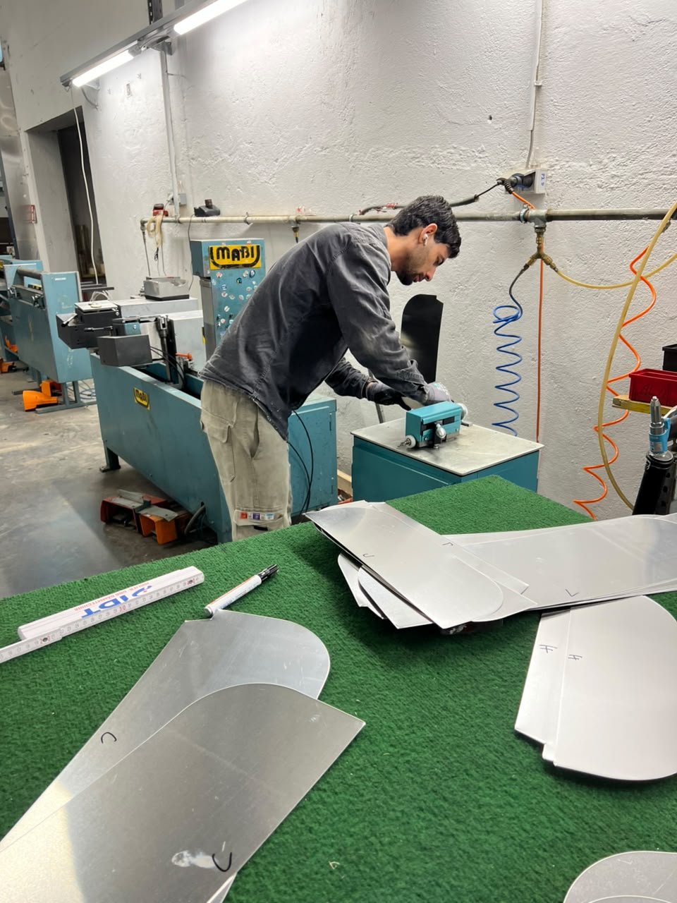Ein Mann arbeitet mit einer Maschine in einer Werkstatt, um Metallteile zu bearbeiten.