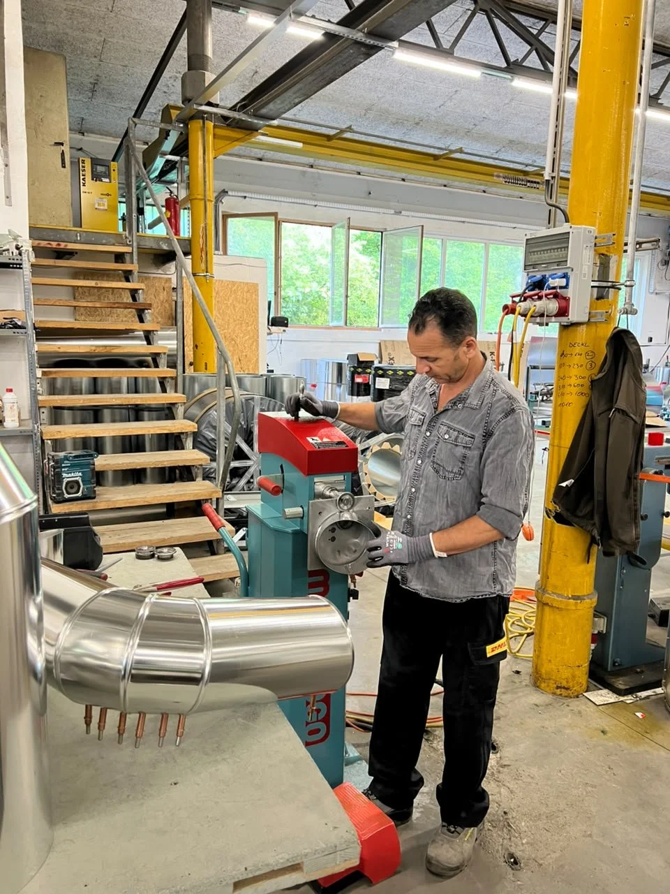 Ein Mann arbeitet mit einer Maschine in einer Werkstatt, auf der er eine Metallprobe hält.