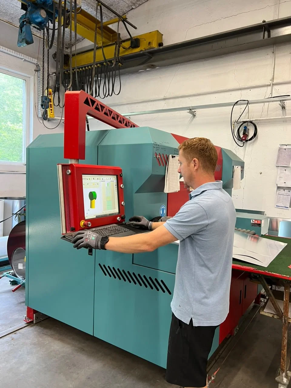 Ein Mann arbeitet an einer CNC-Maschine in einer Werkstatt, während er auf den Bildschirm schaut.