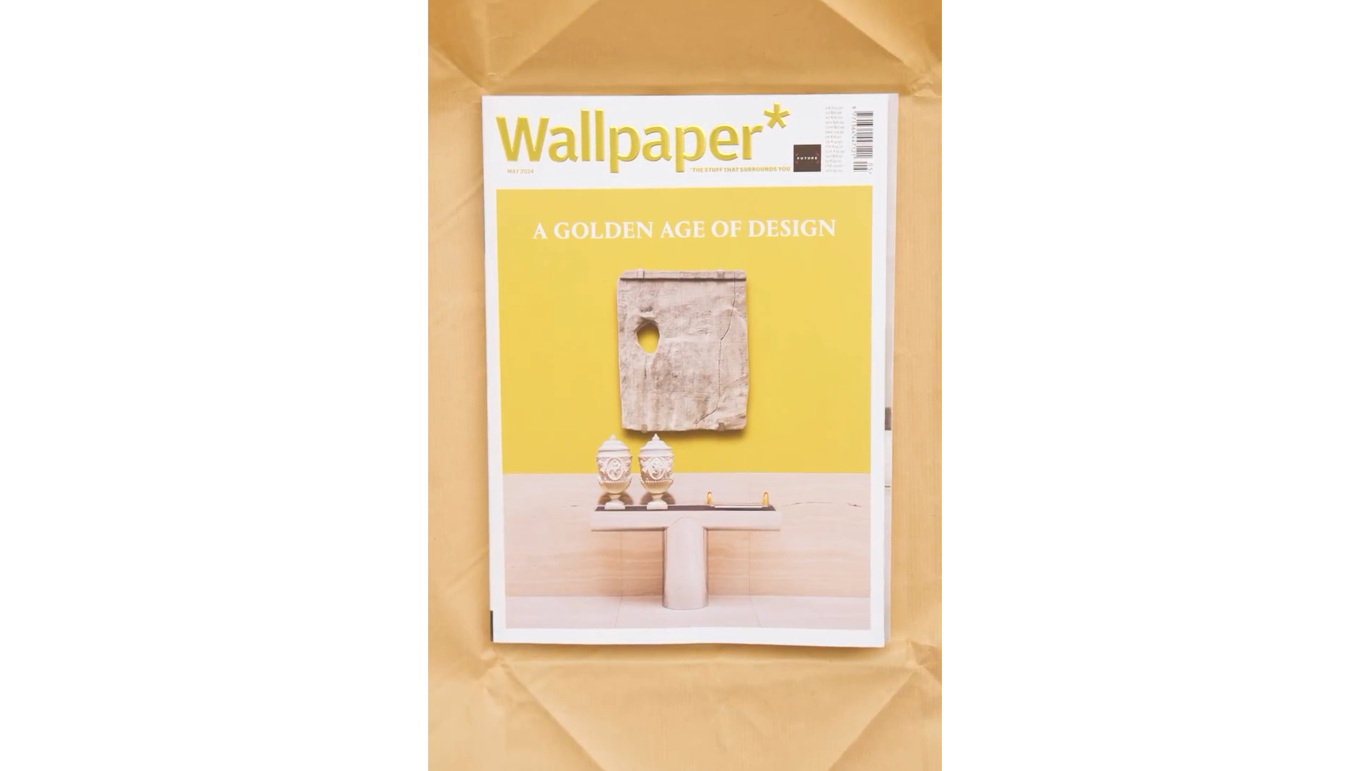 Cover of Wallpaper magazine with the headline 'A GOLDEN AGE OF DESIGN', featuring a wall with a rectangular stone piece with a hole, placed above two classical-style vases and small sculptures on a pedestal.