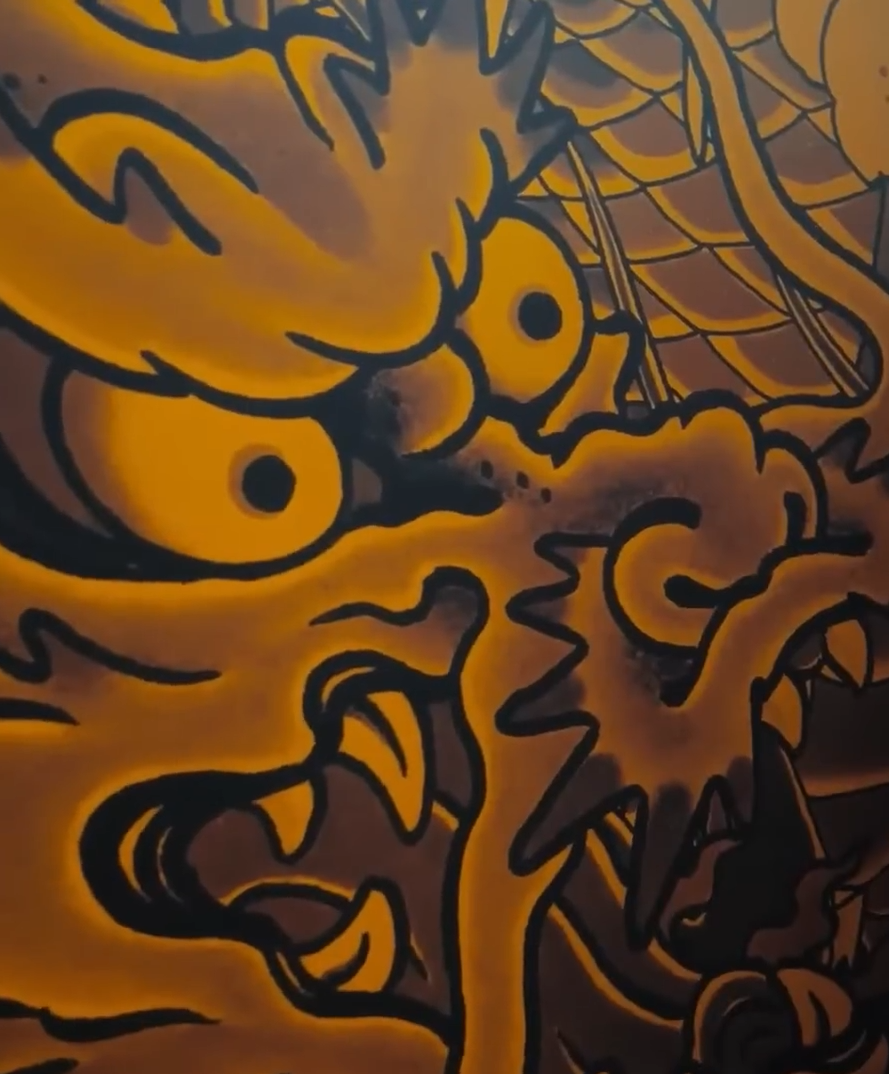 A stylized cartoon dragon with large, expressive eyes, sharp teeth, and fiery orange and yellow coloring.