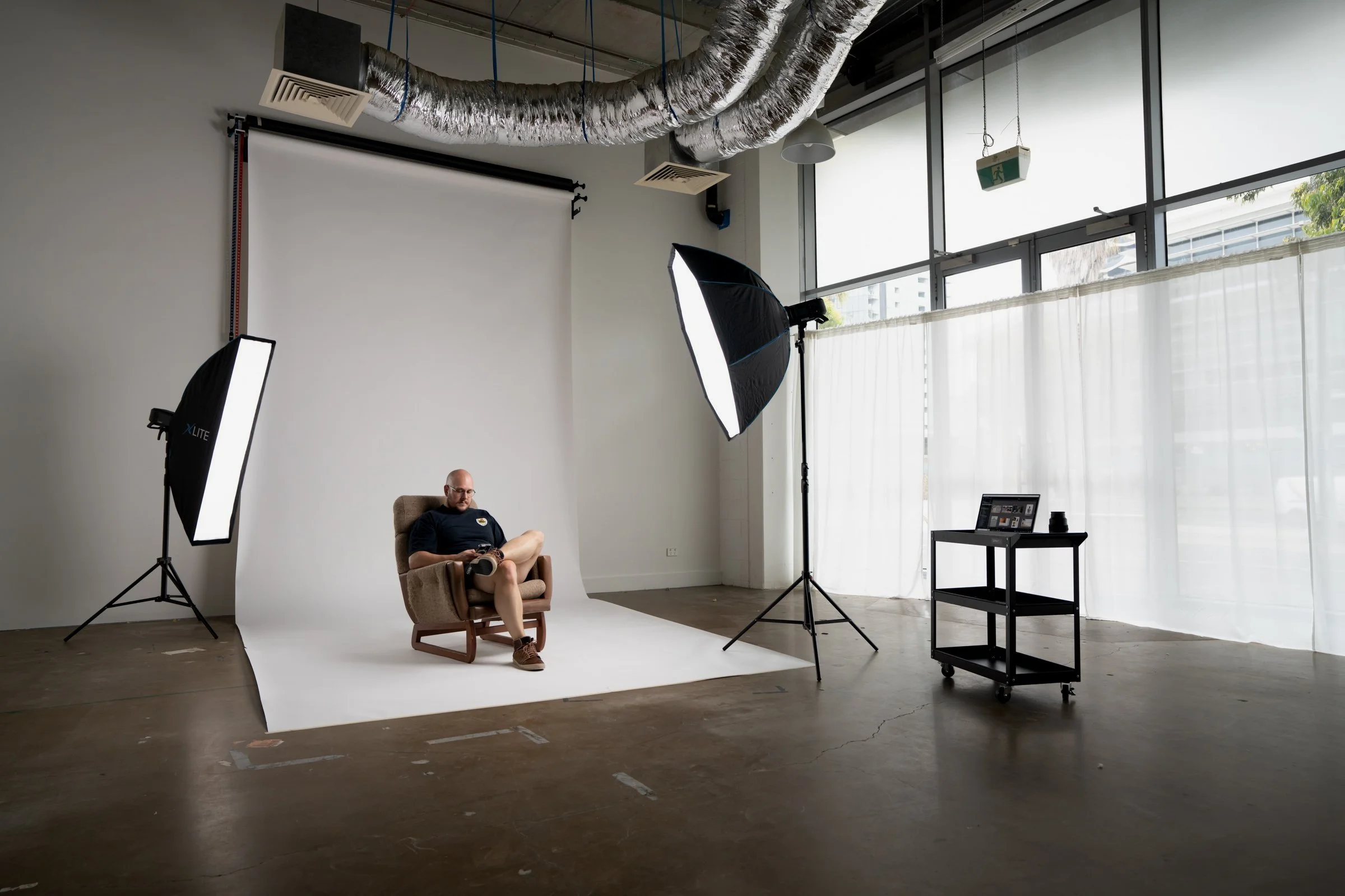 Studio A at Great Space set up with a white seamless paper backdrop, softbox lighting, natural light, and photography equipment ready for a portrait shoot.