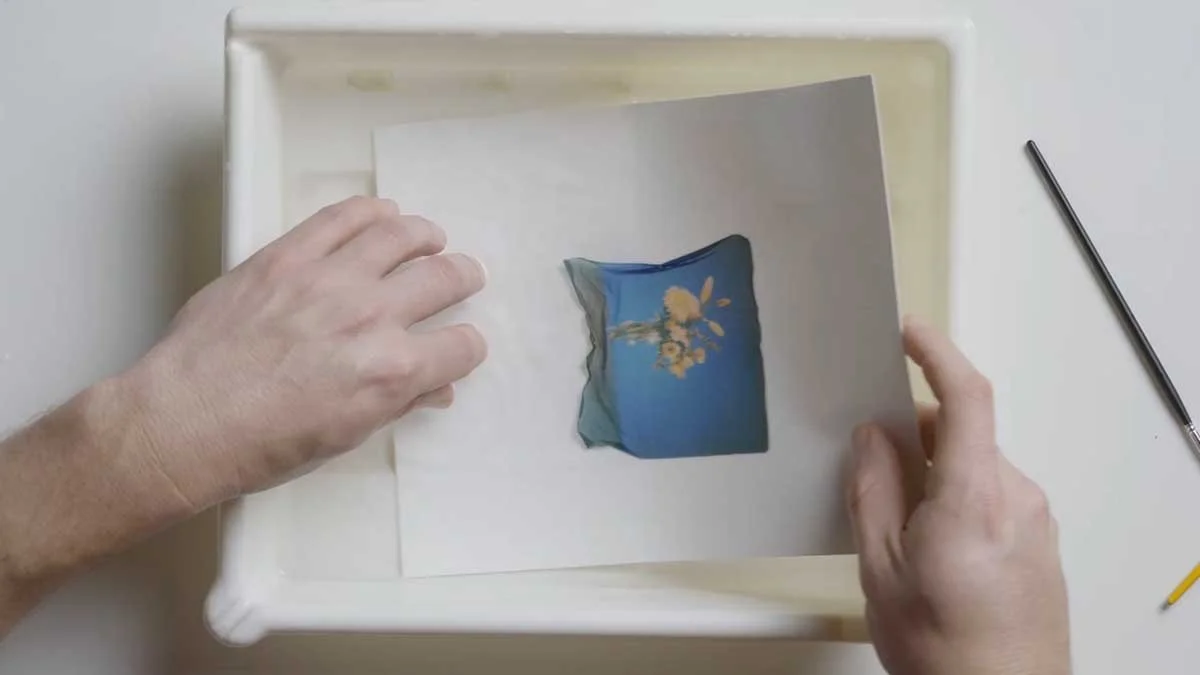 Straightening up the edges of a polaroid lift by dipping it into the water.