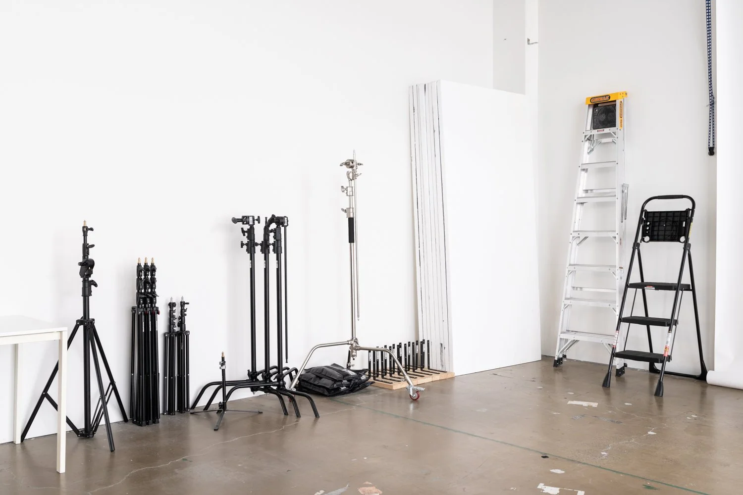 Communal photography equipment at Great Space, including C-stands, light stands, polyboards, a wheeled boom stand, sandbags, and studio accessories.