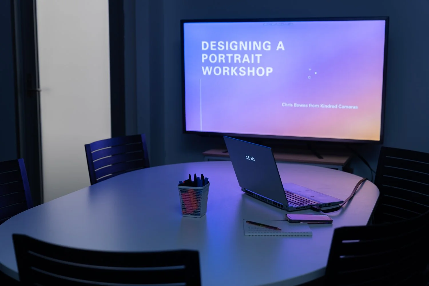 Classroom and meeting space at Great Space with presentation screen, meeting table, and workstation for photography workshops and member collaboration.