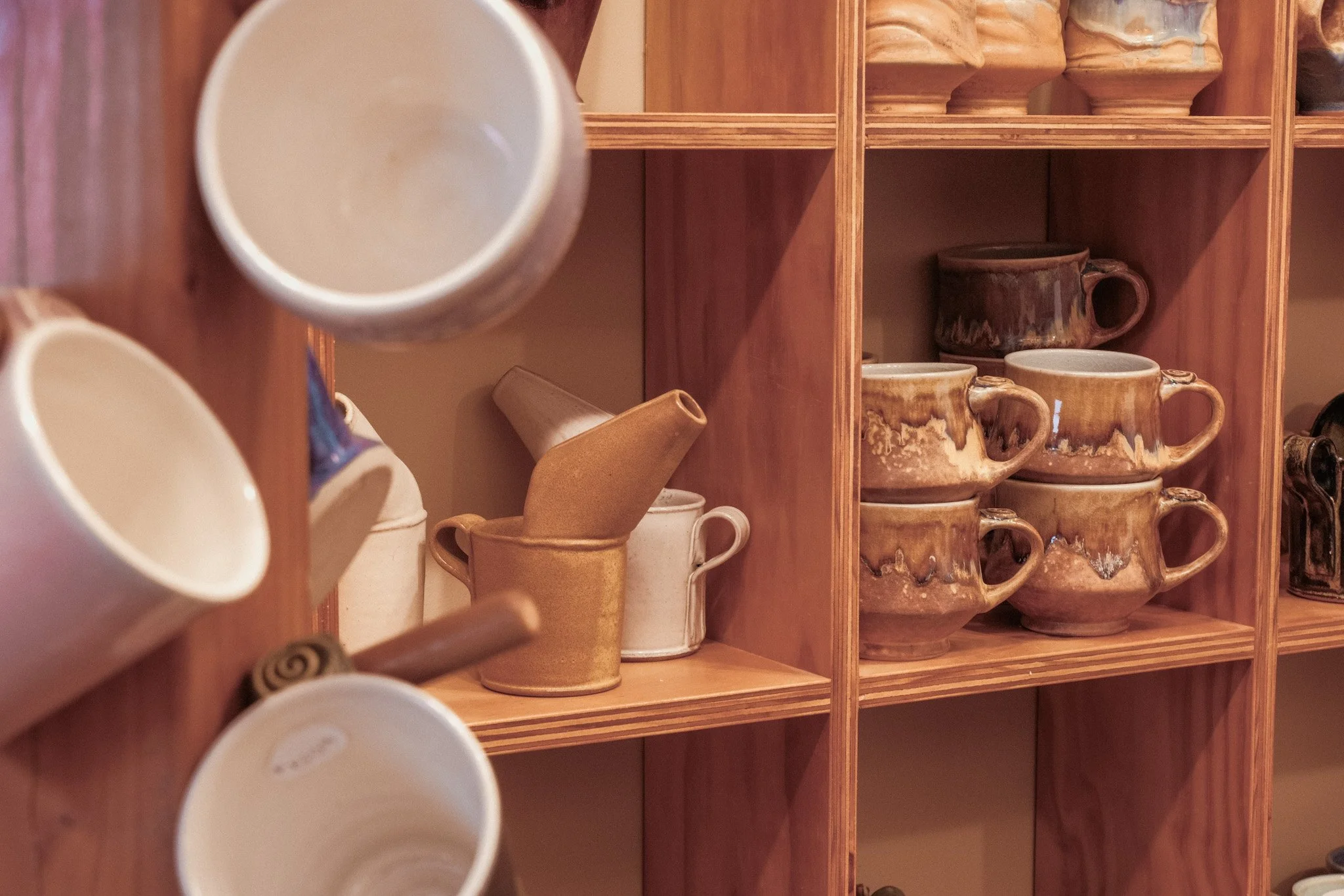 Wooden shelves filled with various ceramic mugs and cups in different shapes and colors.