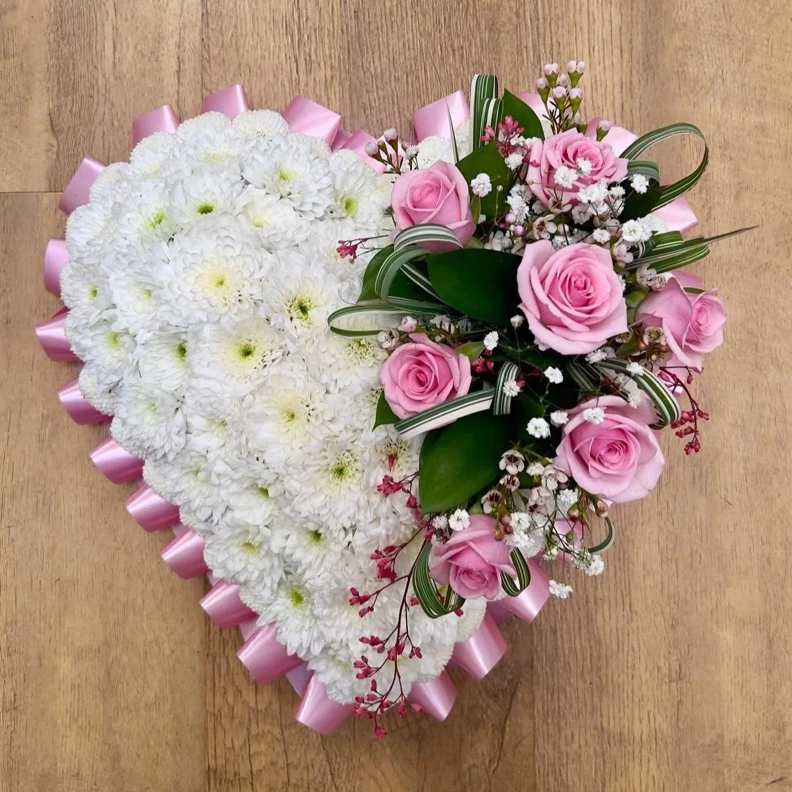 Classic Pink Rose and White Chrysanthemum Solid Heart | A classic, timeless solid heart tribute radiating peace and love. The main body of the heart is crisp white chrysanthemums and surrounded in a light pink pleated ribbon border. An elegant, asymm