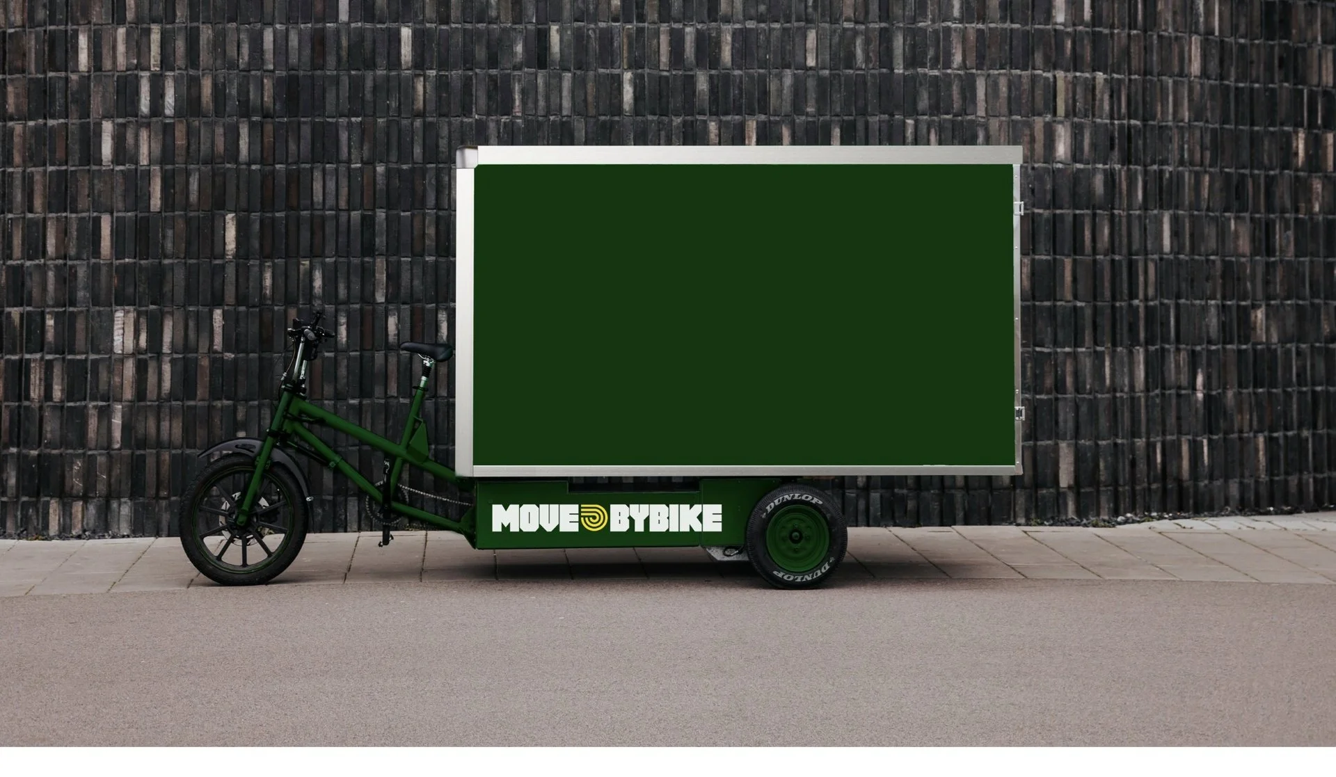 MoveByBikes ellastcykel vid en tegelvägg.