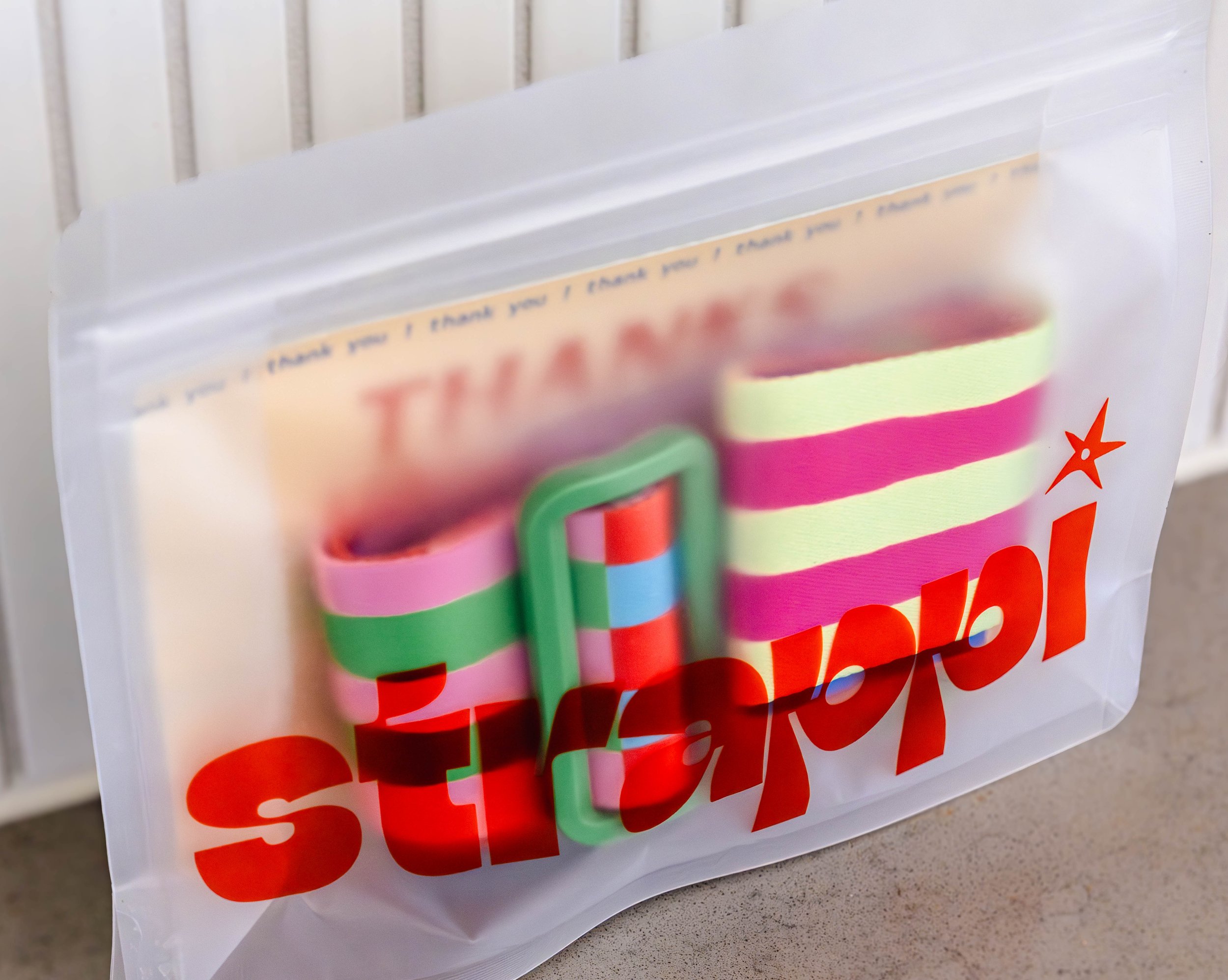 Close-up of a colorful patterned party favor bag with a message in blue and red text, featuring various vibrant colors and a small orange star at the bottom right.
