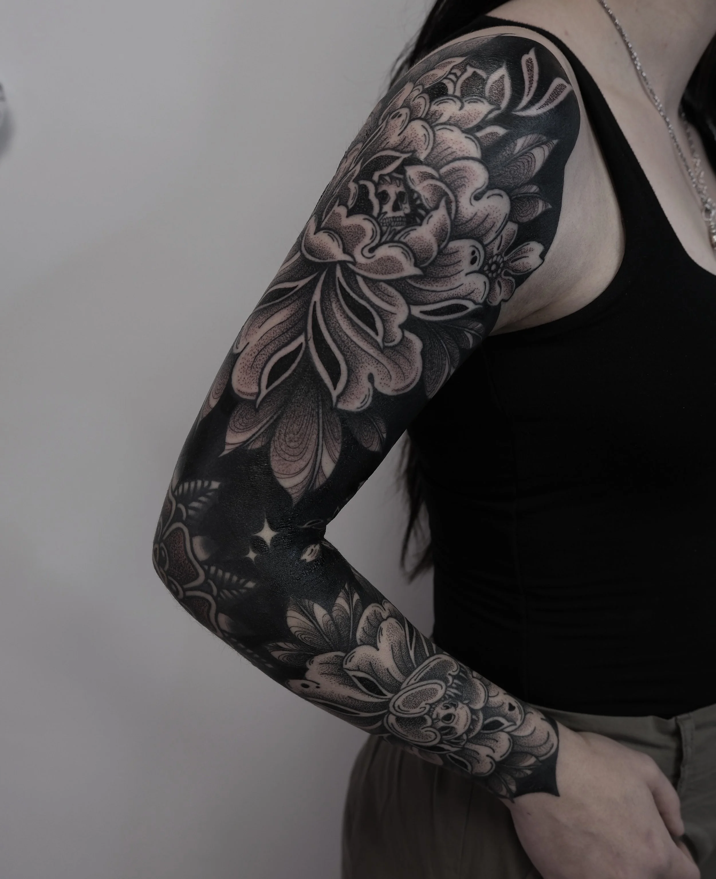 Spooky peonies 💀 🎃 🖤 

Full negative sleeve. Tamsin had a colour traditional elbow banger we dotted over to dull the colour down and integrate it into the new sleeve abit better 

Dotwork shading on the shoulder is fresh, Took this 📷 4 days into 