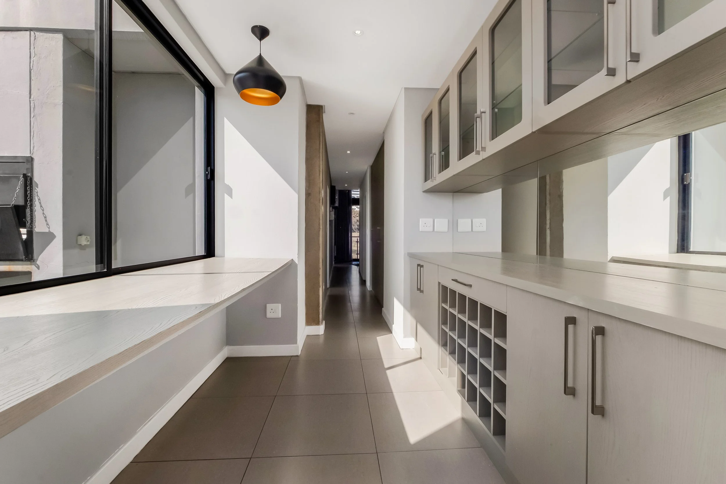 Modern kitchen with white cabinets, a built-in wine rack, and a large window bringing in natural light.
