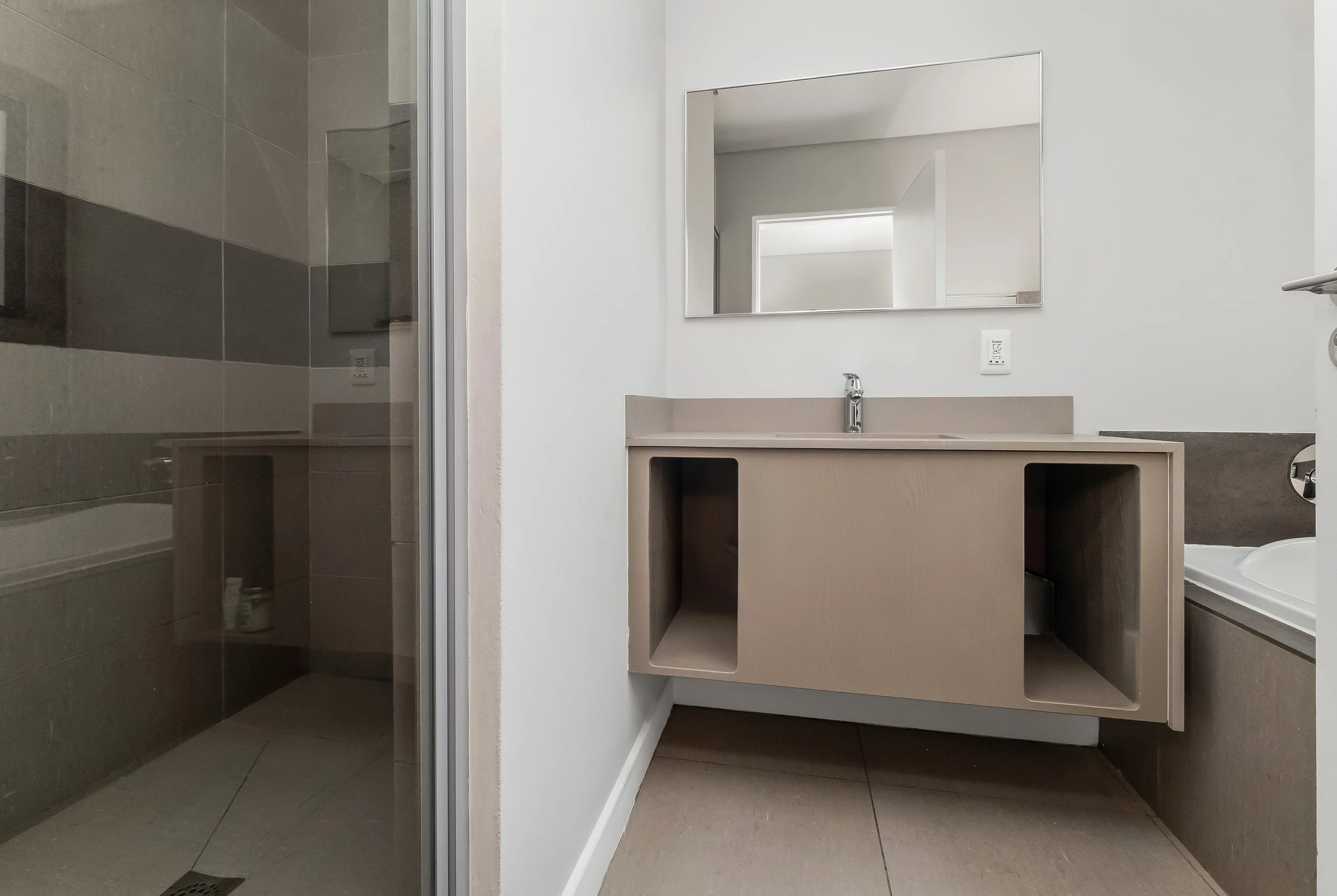 Modern bathroom with a sink and a mirror, featuring a minimalist design with beige and grey color tones.