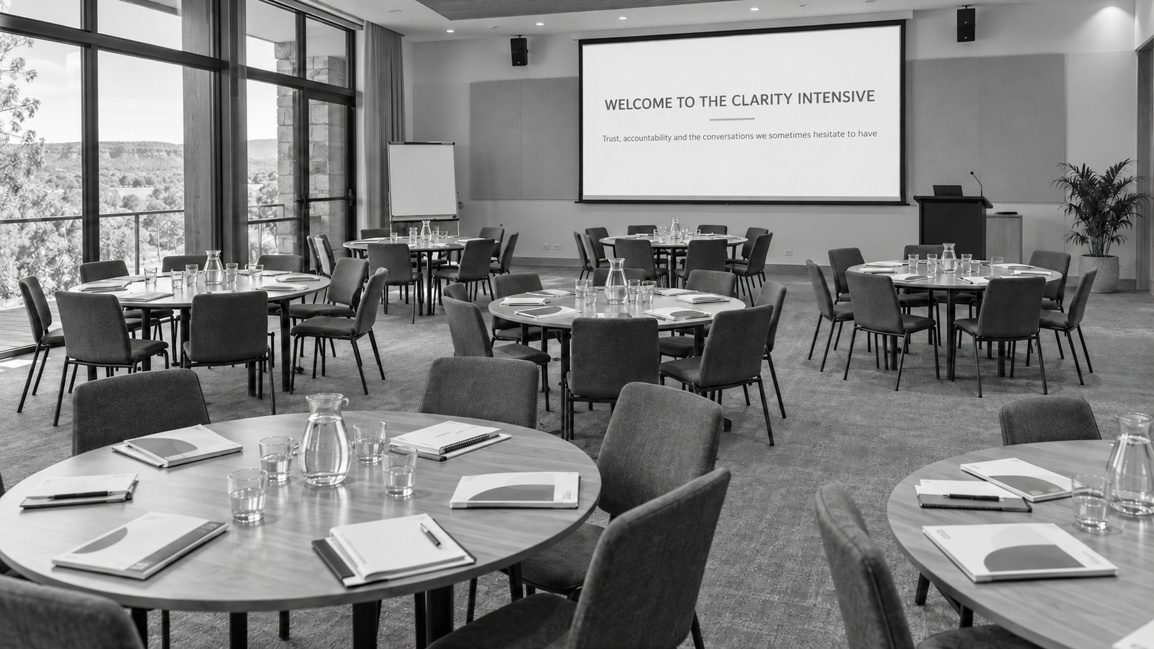 Professional-learning room prepared with round tables, participant resources and water glasses.