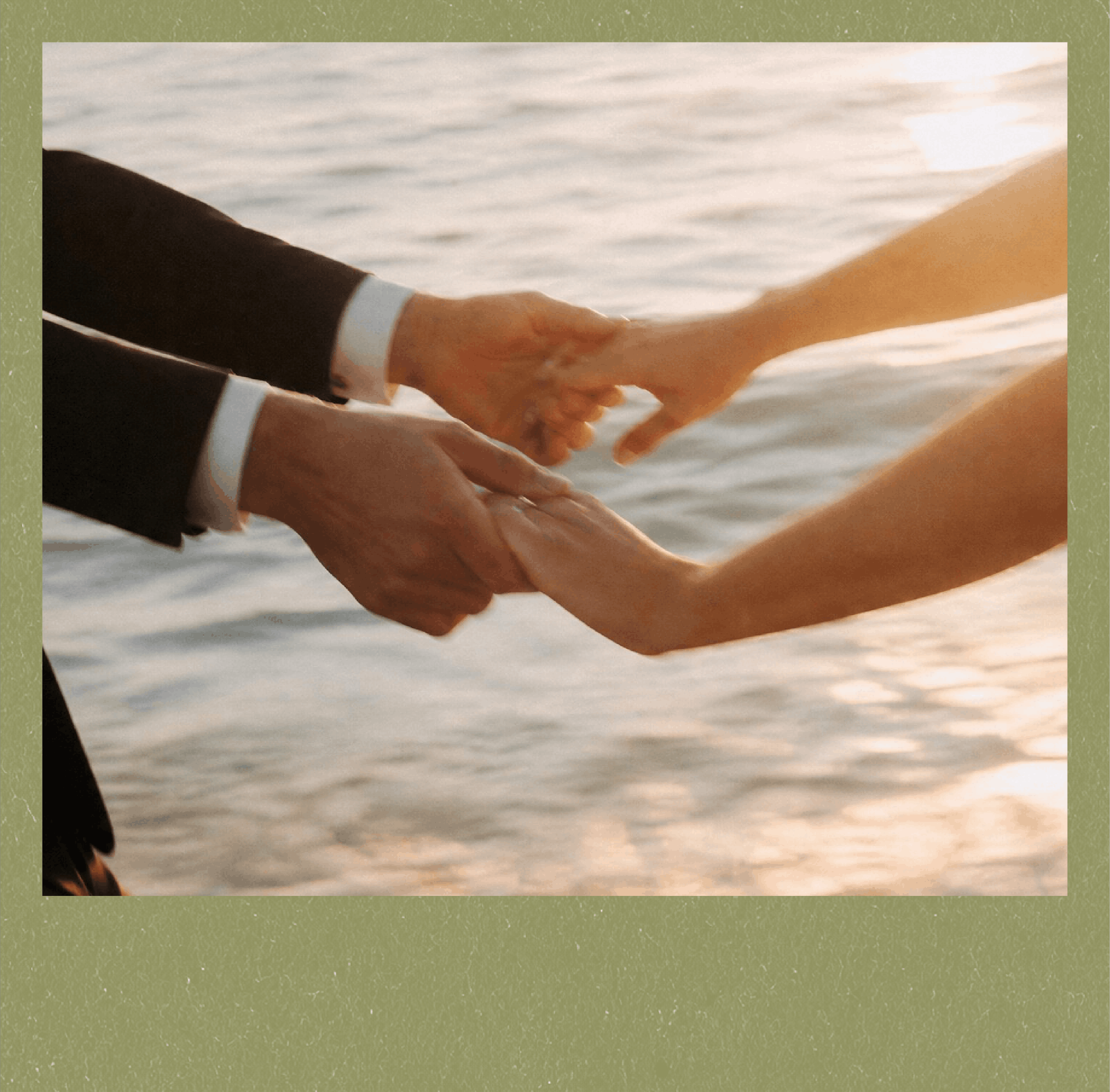 Two people holding hands near the water during sunset.
