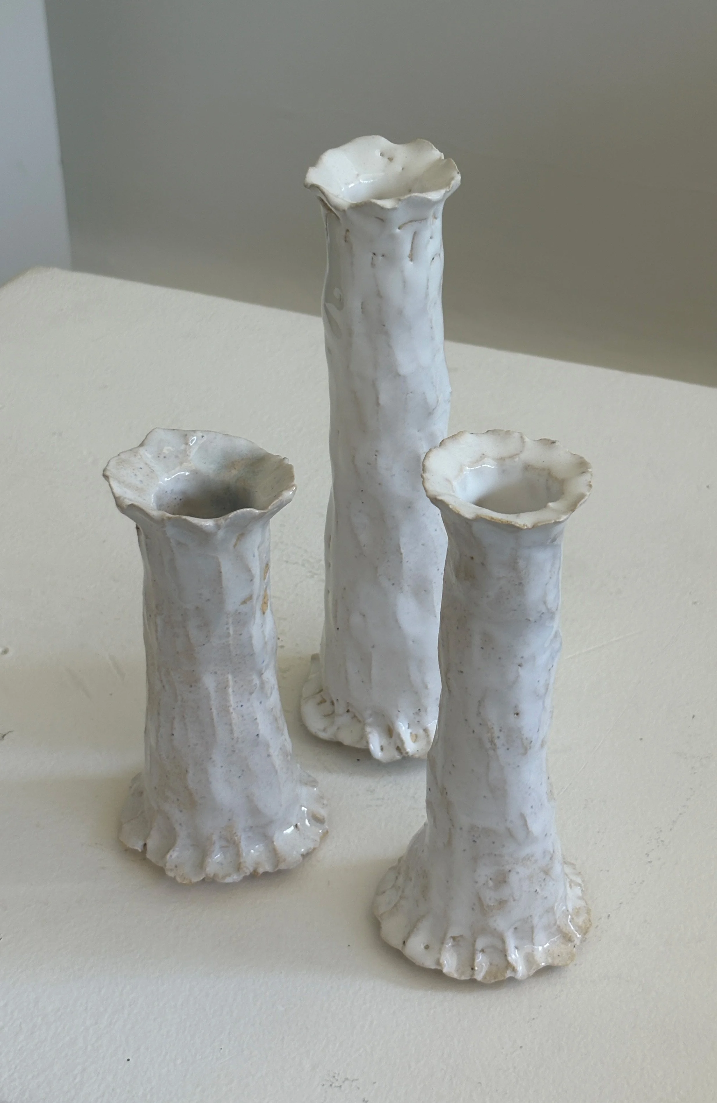 White ceramic candle holders resembling sea shells with tall, irregularly shaped bases.