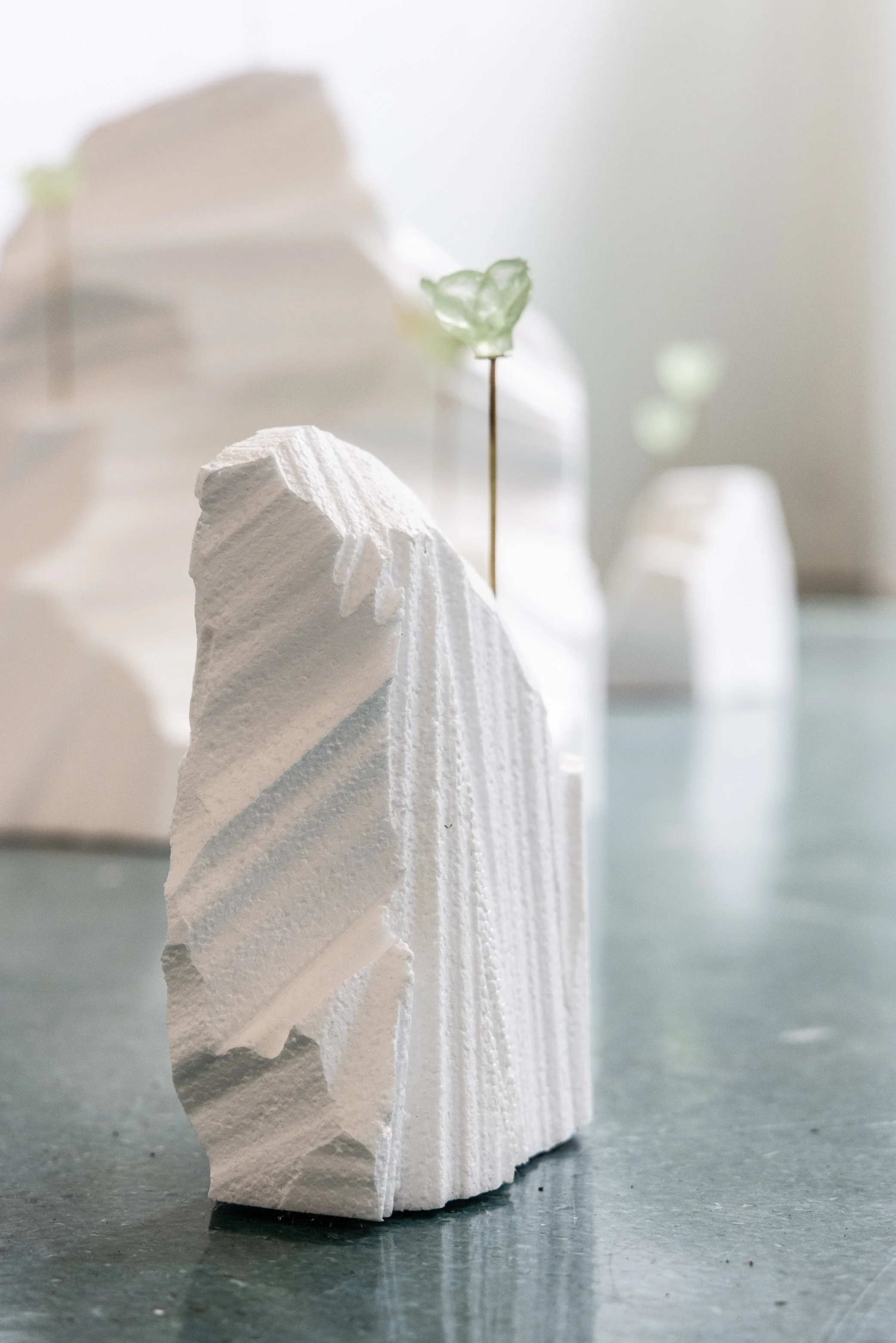 A sculpture of a dog or wolf made from white textured material, with a second sculpture in the background.