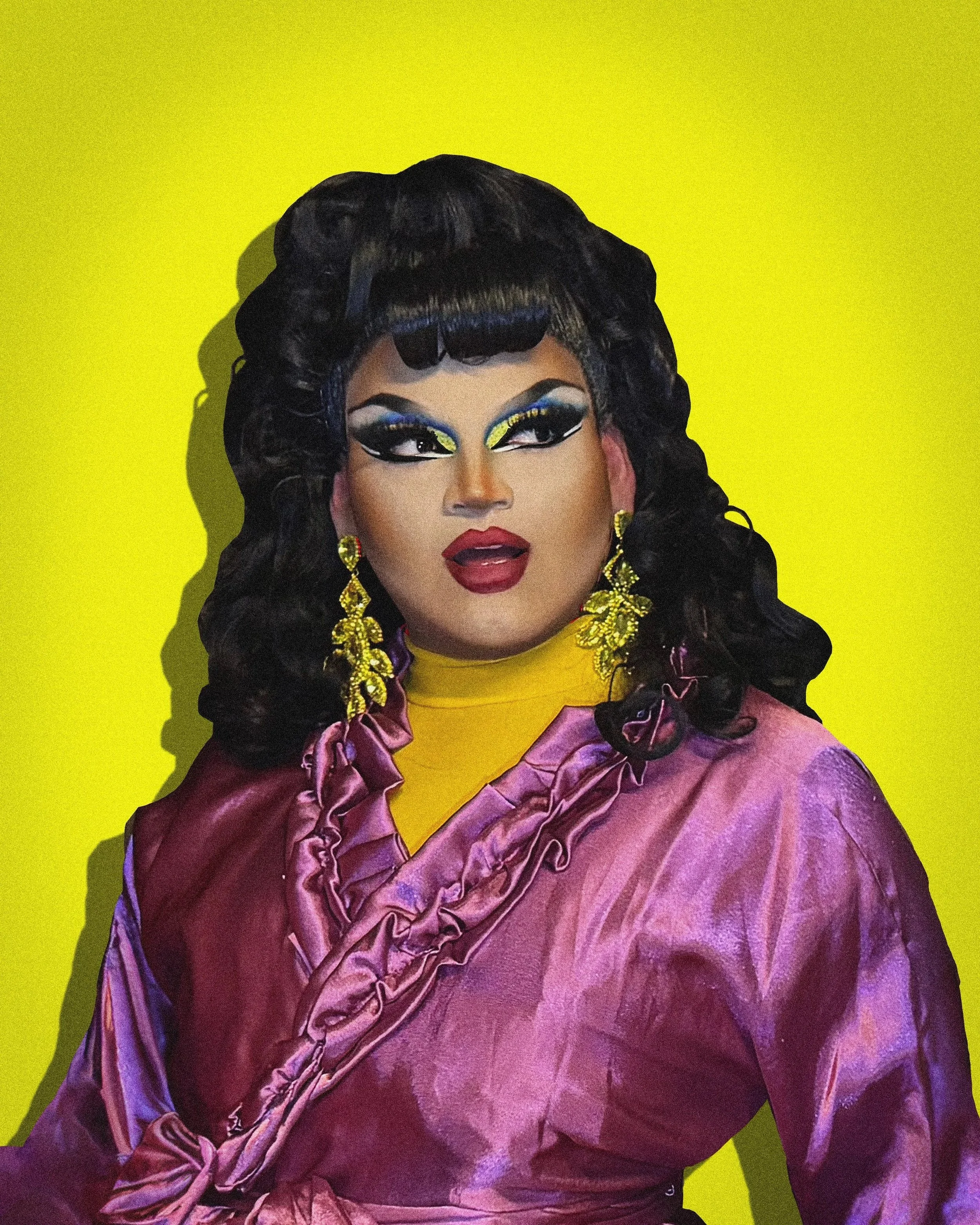 Un portrait d'une drag queen avec des cheveux noirs bouclés, du maquillage coloré, des boucles d'oreilles dorées et un vêtement violet, sur un fond jaune.