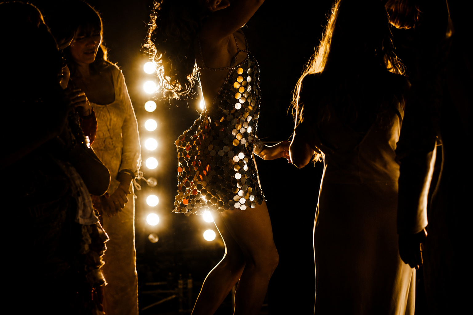 Groupe de femmes en vêtements brillants lors d'une soirée avec éclairage intense en arrière-plan.