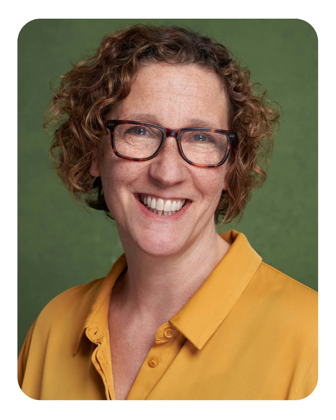 Jessie Cunnett, a woman with short curly hair wearing glasses, smiles into the camera