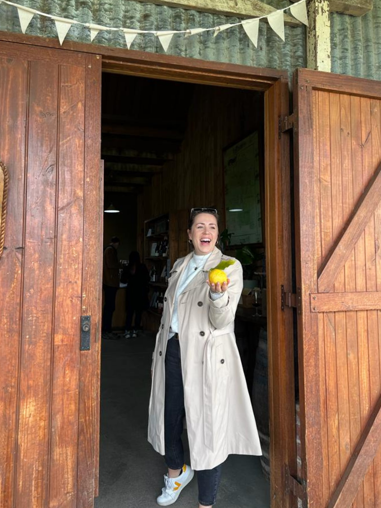 Morwenna holding a large lemon in front of a barn