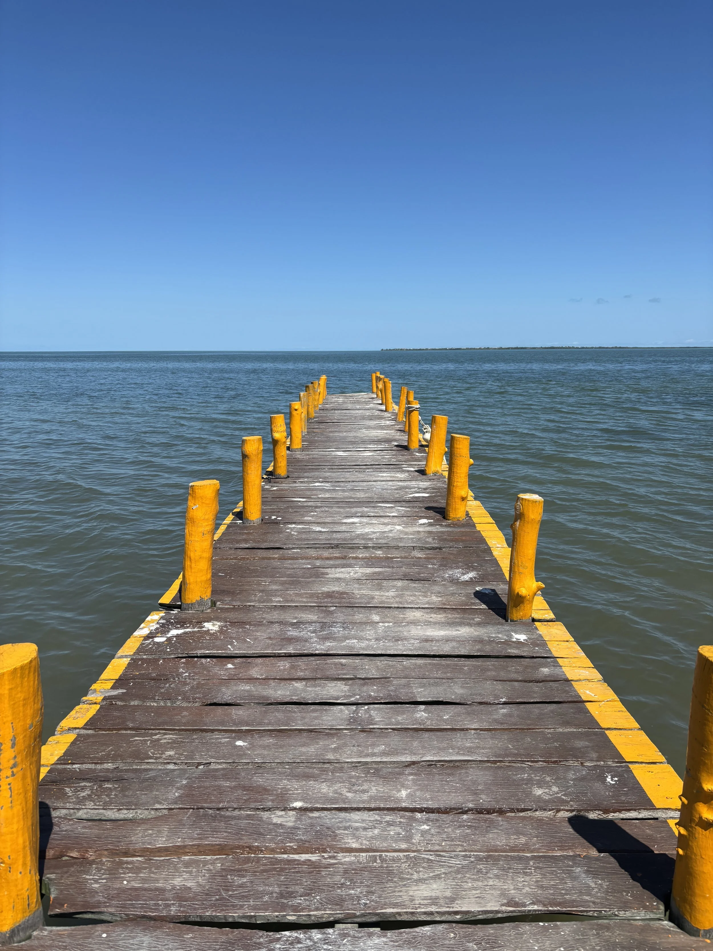 Bright yellow pier leading out to the horizon in Holbox, Mexico
