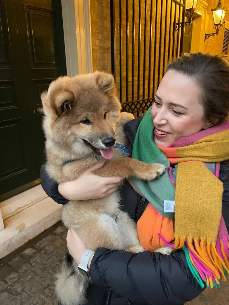Morwenna wearing a colourful scarf and holding a fluffy dog
