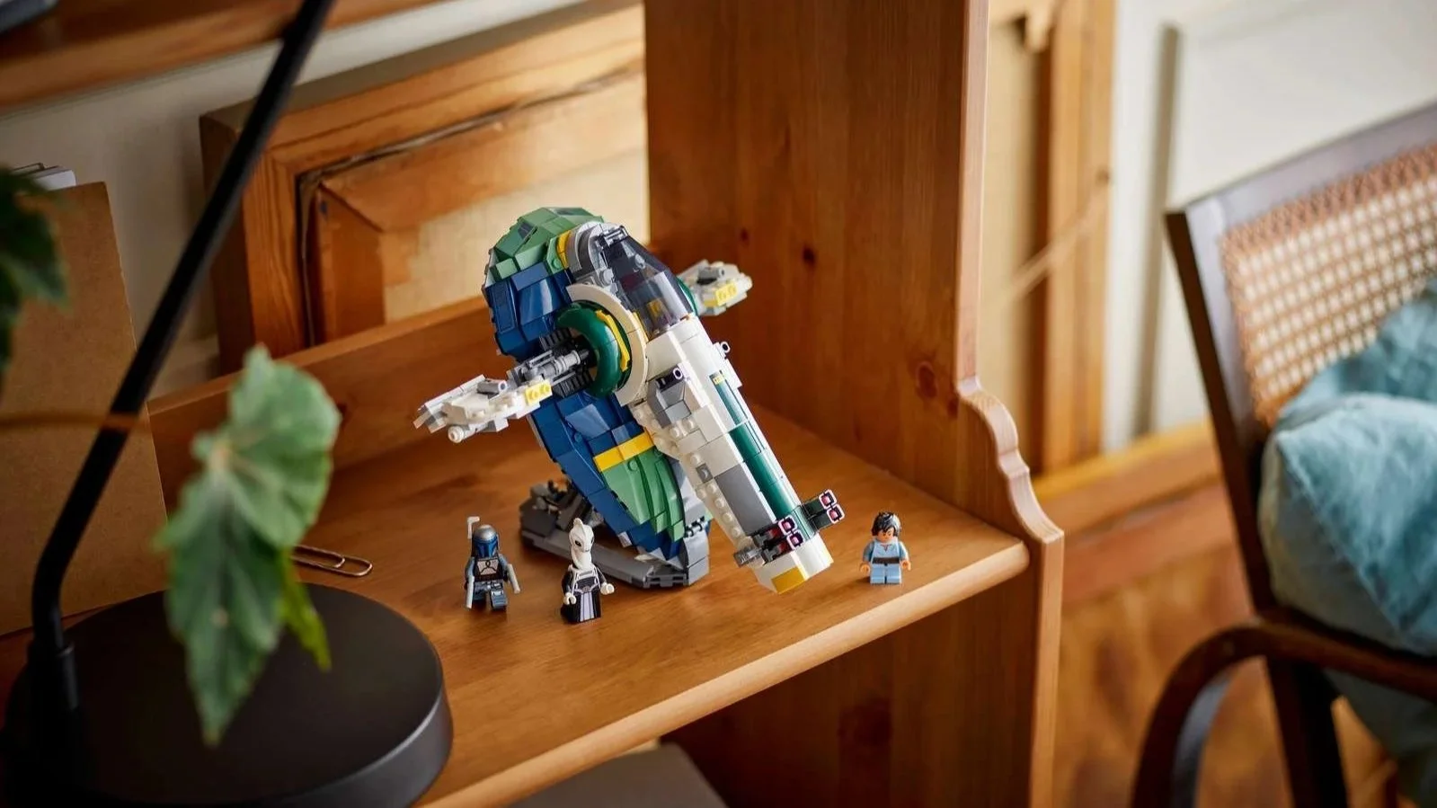 LEGO Star Wars Jango Fett’s Starship in blue, green and white on a wooden shelf with three minifigures in front