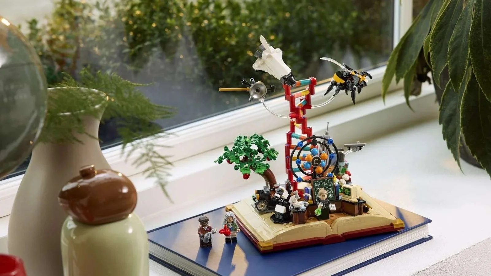 LEGO Evolution of STEM set on a sunlit windowsill, with garden greenery outside and two minifigures posed by its storybook base