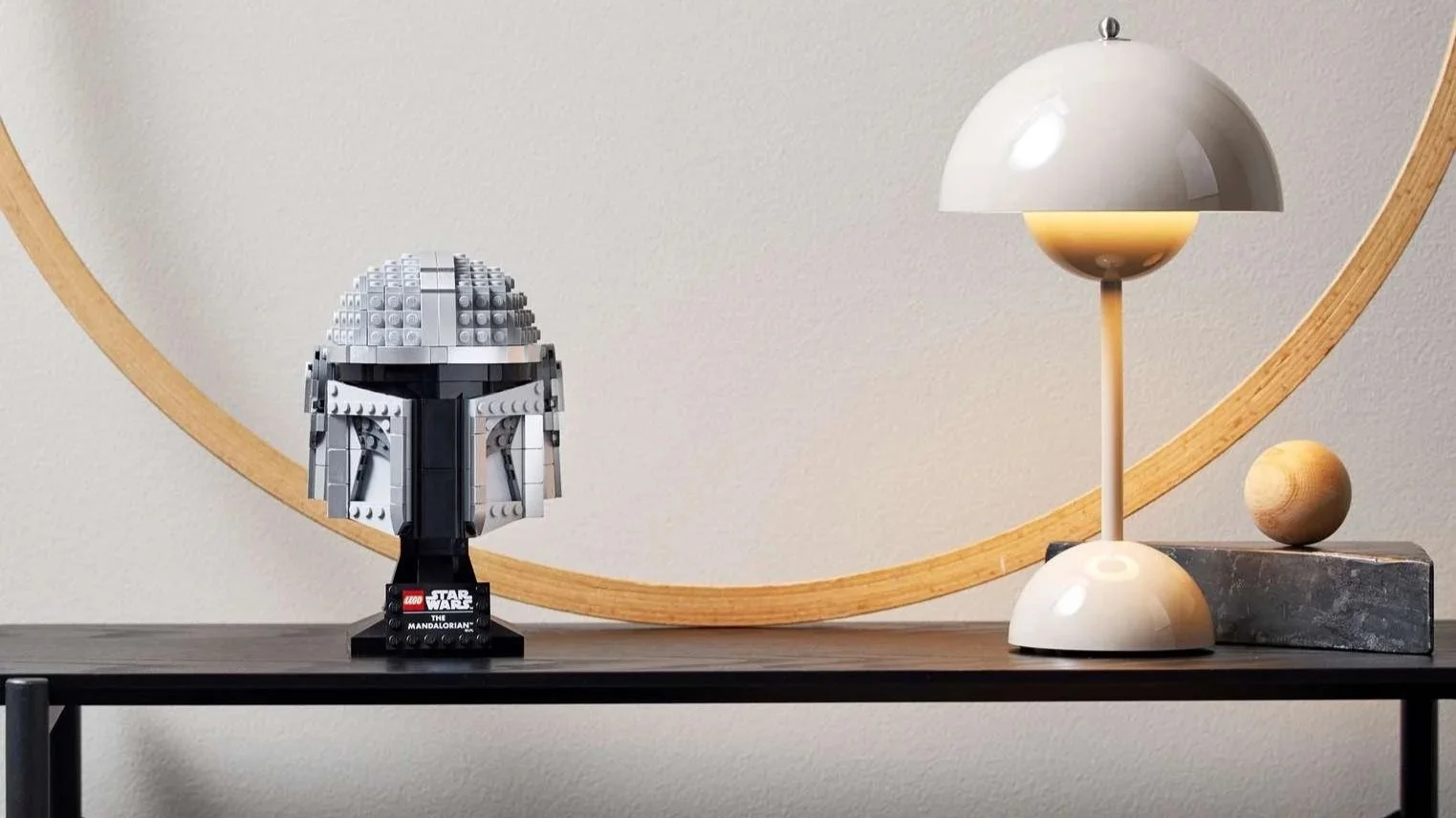 LEGO Star Wars The Mandalorian Helmet on a black console table next to a modern dome table lamp