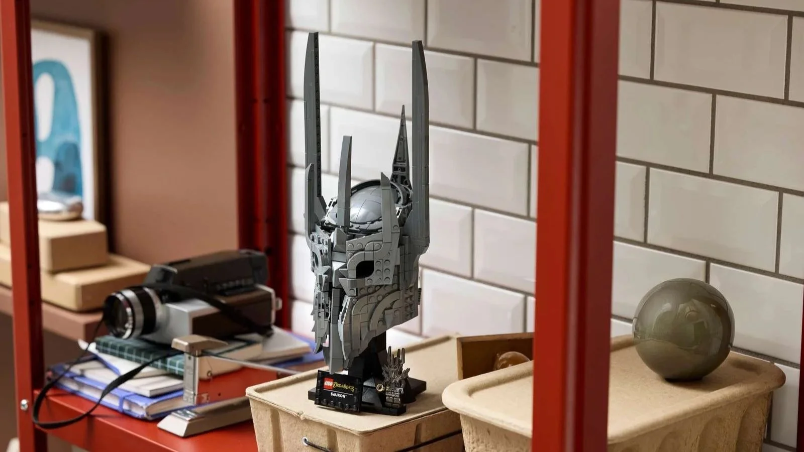 Brick-built LEGO Sauron's Helmet set from The Lord of the Rings on a red shelf against white subway tile