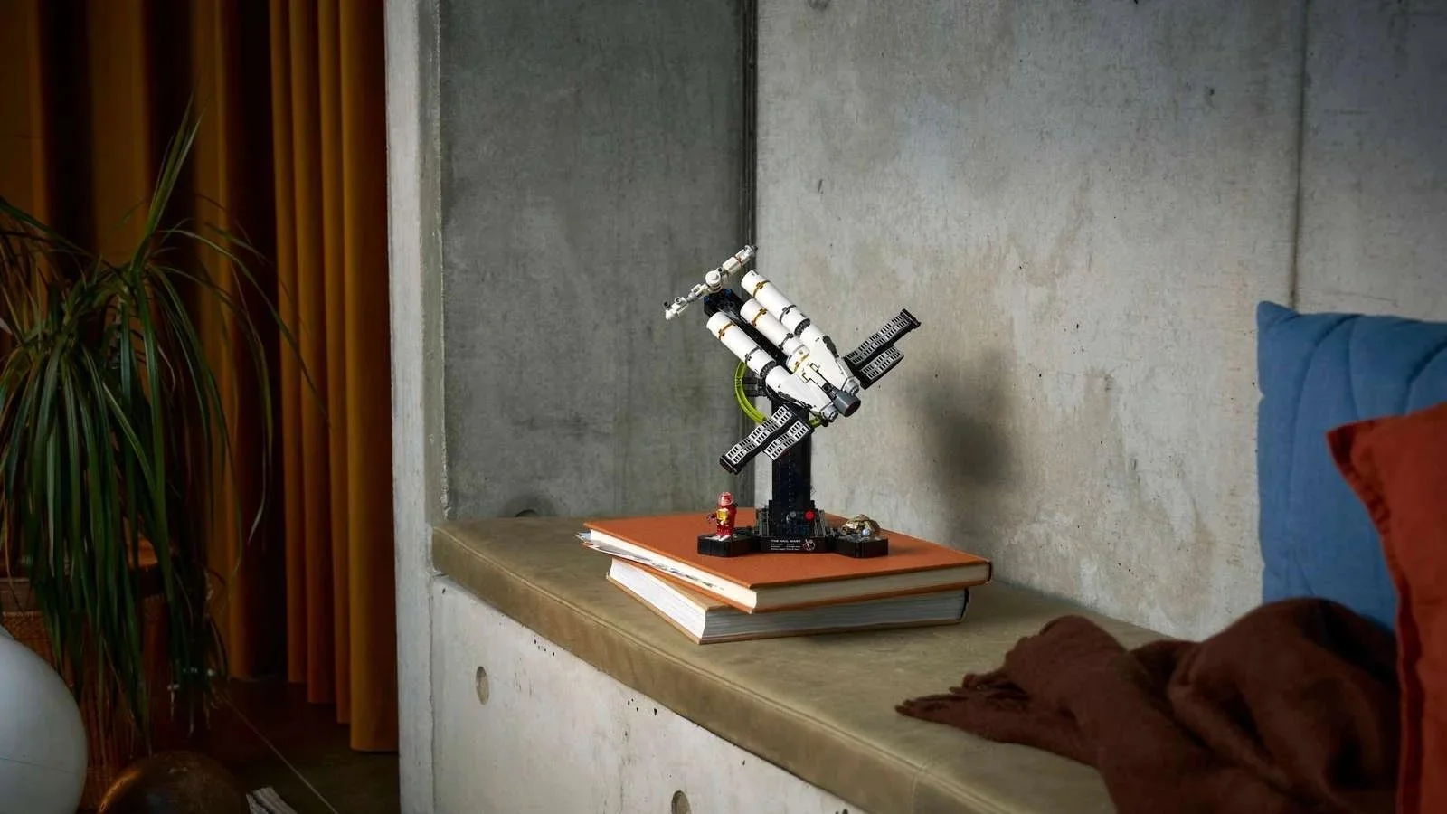 LEGO Project Hail Mary spaceship set with a small astronaut figure displayed on books on a concrete ledge