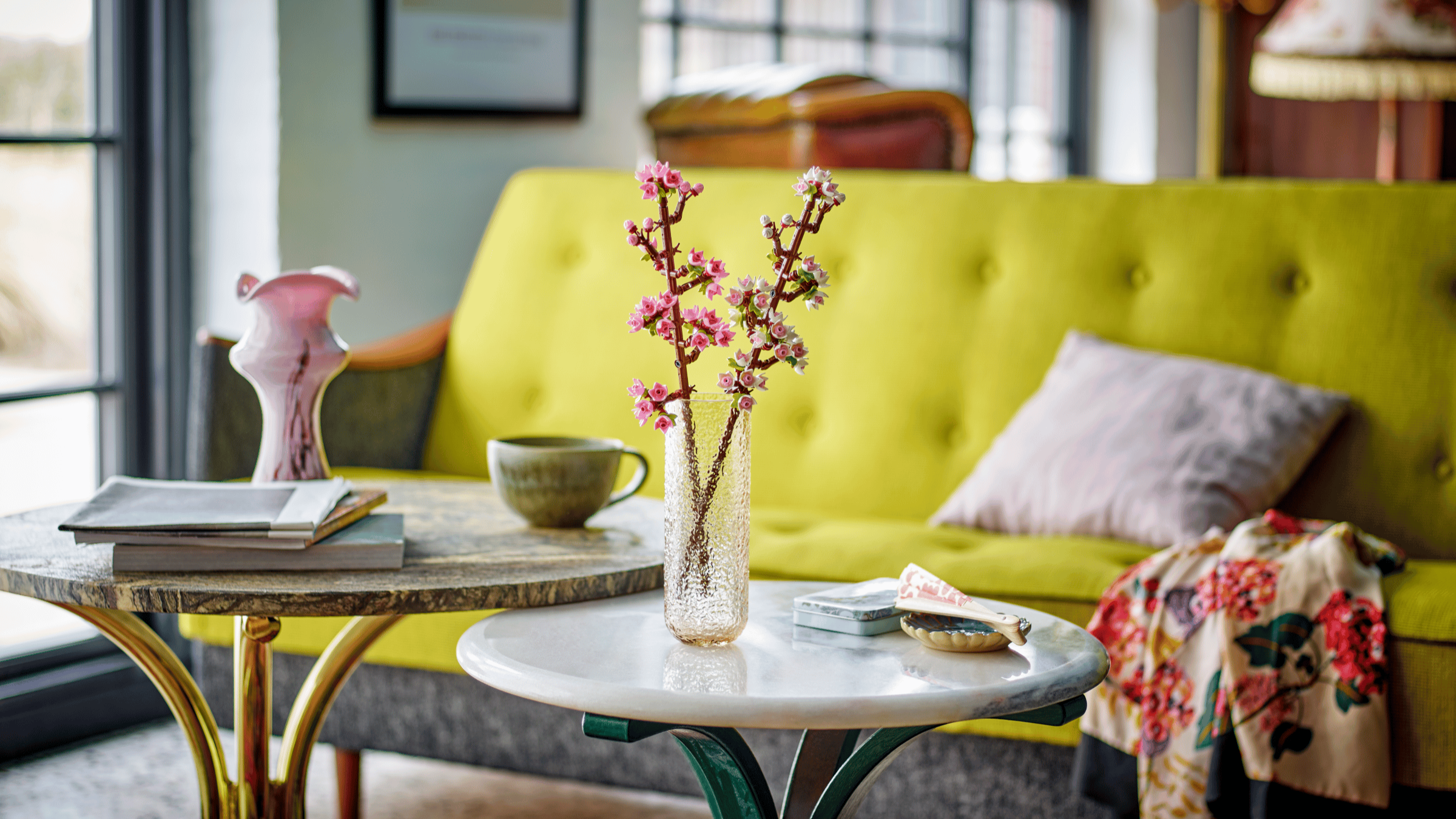 LEGO Cherry Blossoms in a textured glass vase on a marble side table by a bright chartreuse sofa