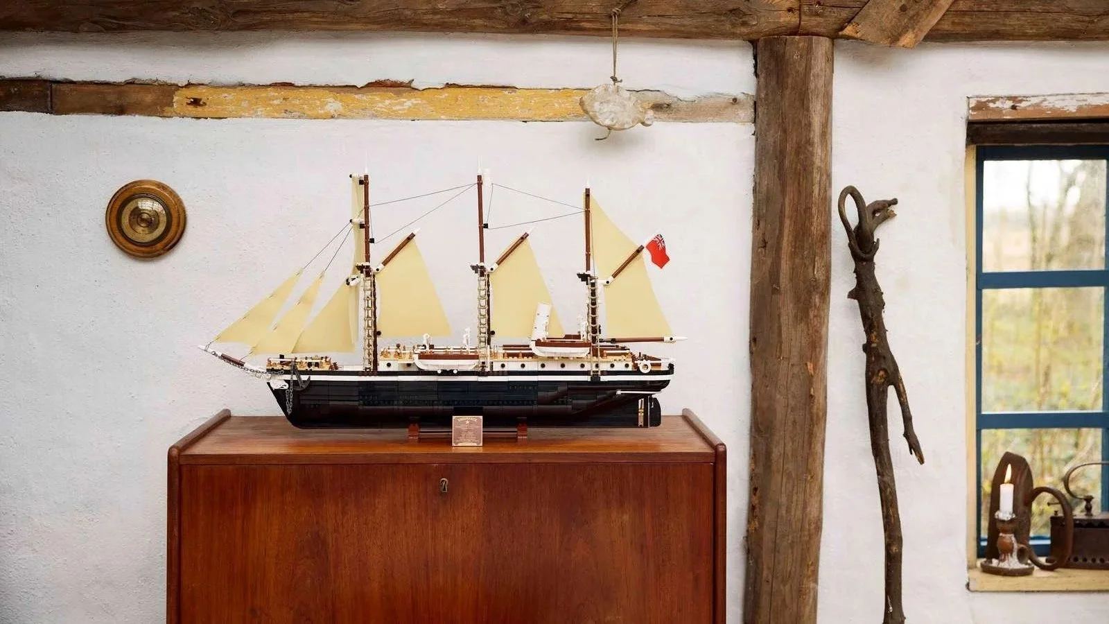 LEGO Endurance ship model with tan sails displayed on a wood cabinet in a rustic room